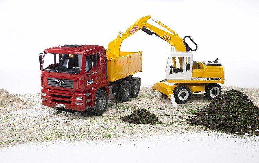 Bruder Liebherr excavator loading soil into the MAN TGA construction truck in an outdoor play scene