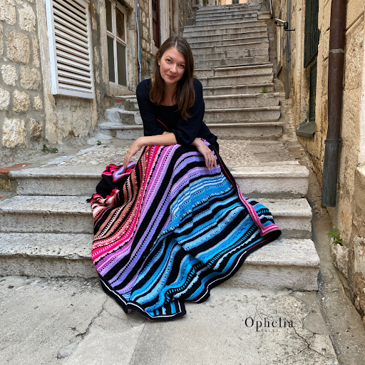 anja from ophelia talks crochet sat on step wearing colourful skirt