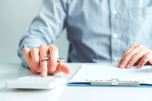 Businessman calculating costs using calculator and note pad