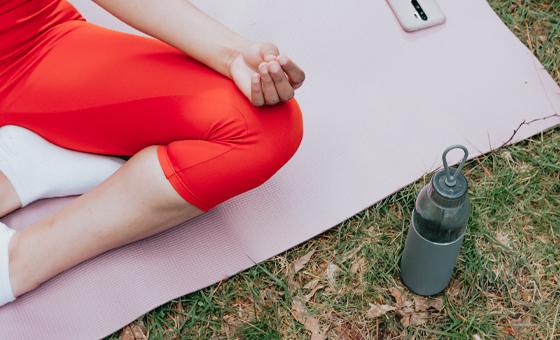 lady on a yoga mat with a mobile phone and water bottle nearby