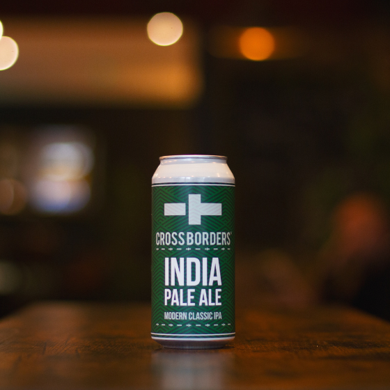 A can of beer with a dark green label which reads "India Pale Ale", on a wooden table.