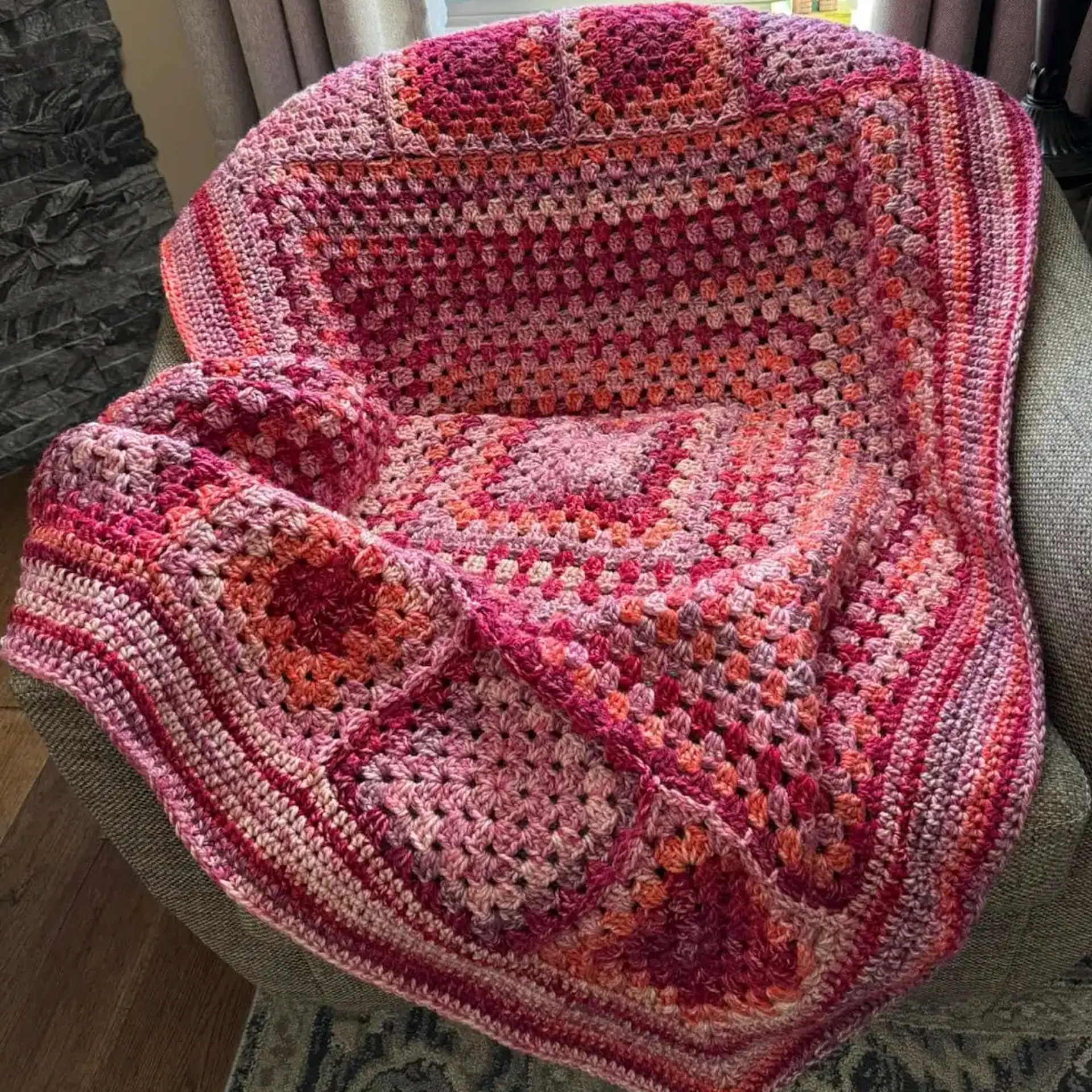 Crocus crochet blanket made with King Cole Hedgerow Chunky yarn, colour Holly Berry, chunky acrylic yarn showing textured granny stitch blanket in pink and berry tones.