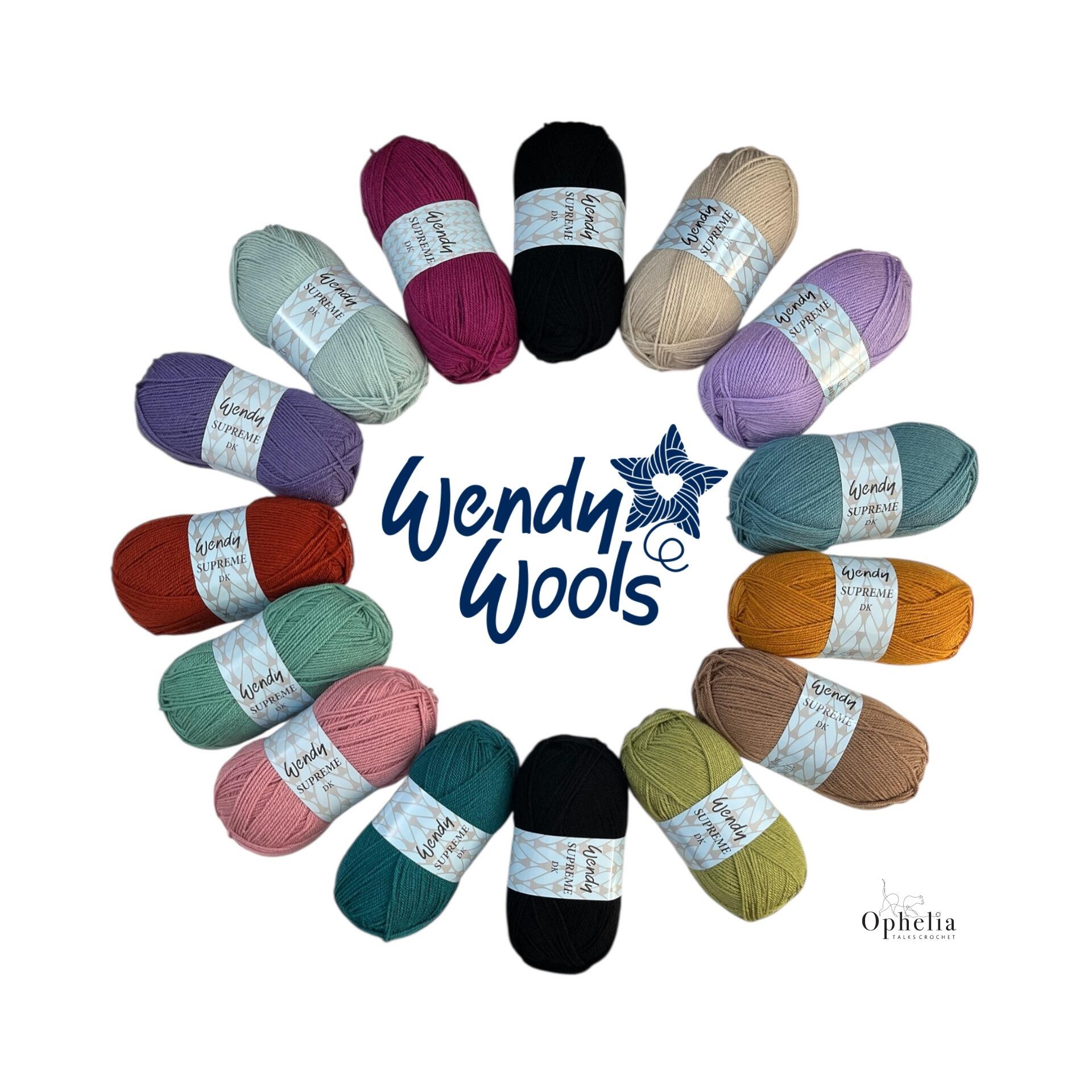 A circular arrangement of 18 balls of Wendy Supreme DK yarn in a variety of soft and bold colors, forming the yarn pack for the Anniversary Blanket by Ophelia Talks Crochet. The Wendy Wools logo is centered in the middle, with the Ophelia Talks Crochet logo in the lower right corner, all set against a clean white background.