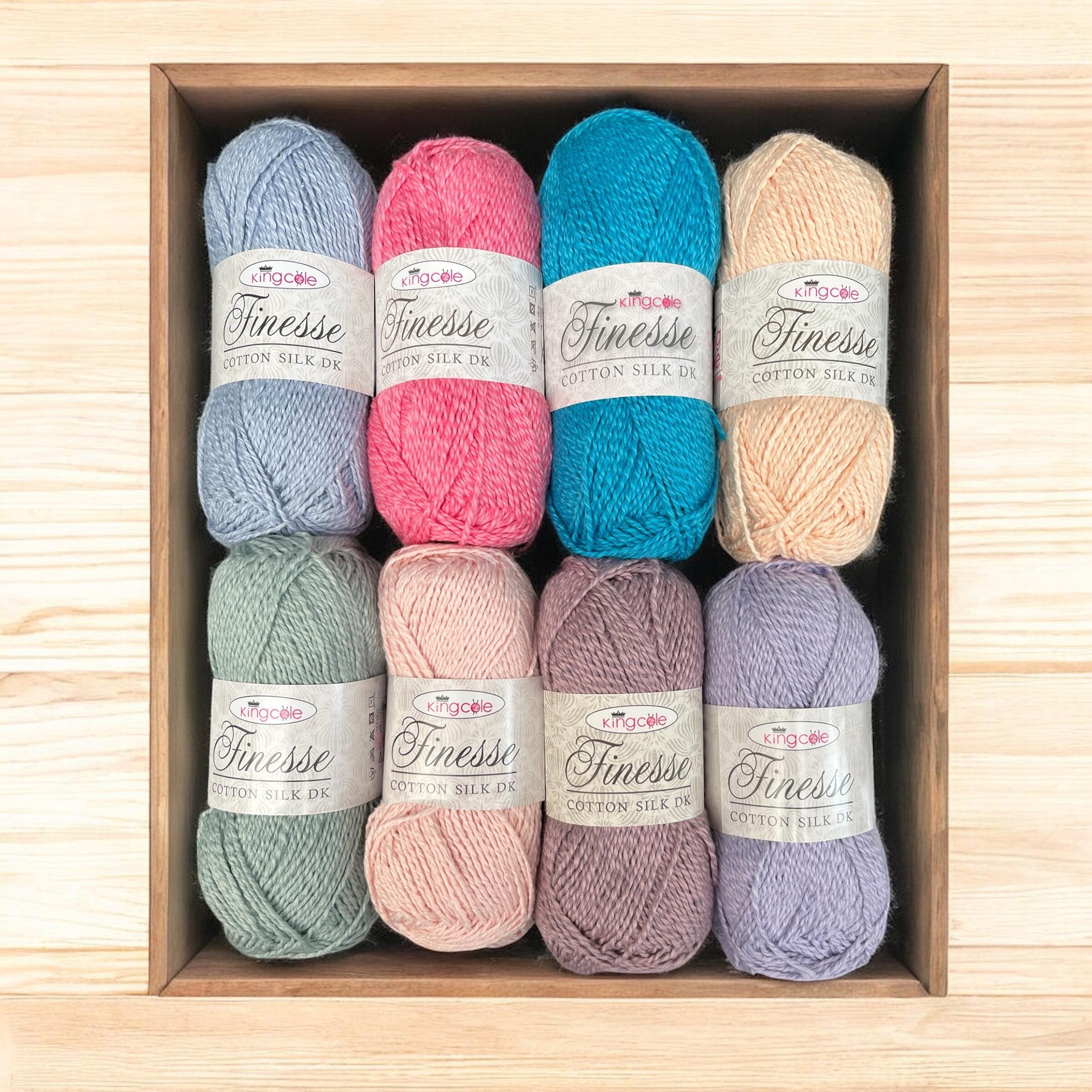 King Cole Finesse Cotton Silk DK yarn bundle in pastel shades, displayed in a wooden tray