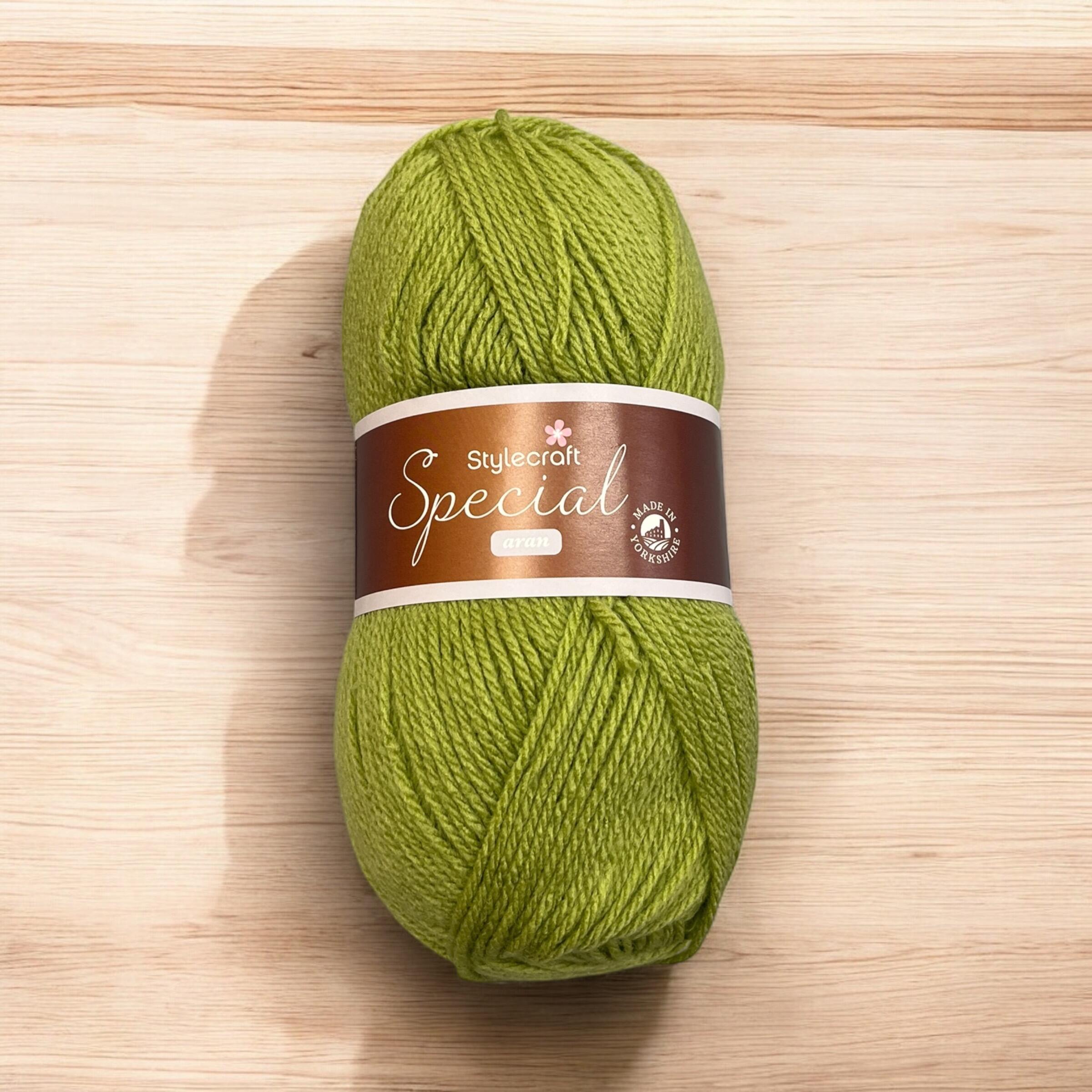 alt="A ball of Stylecraft Special Aran yarn in a bright green shade, placed on a light wooden surface" Aran yarn ball