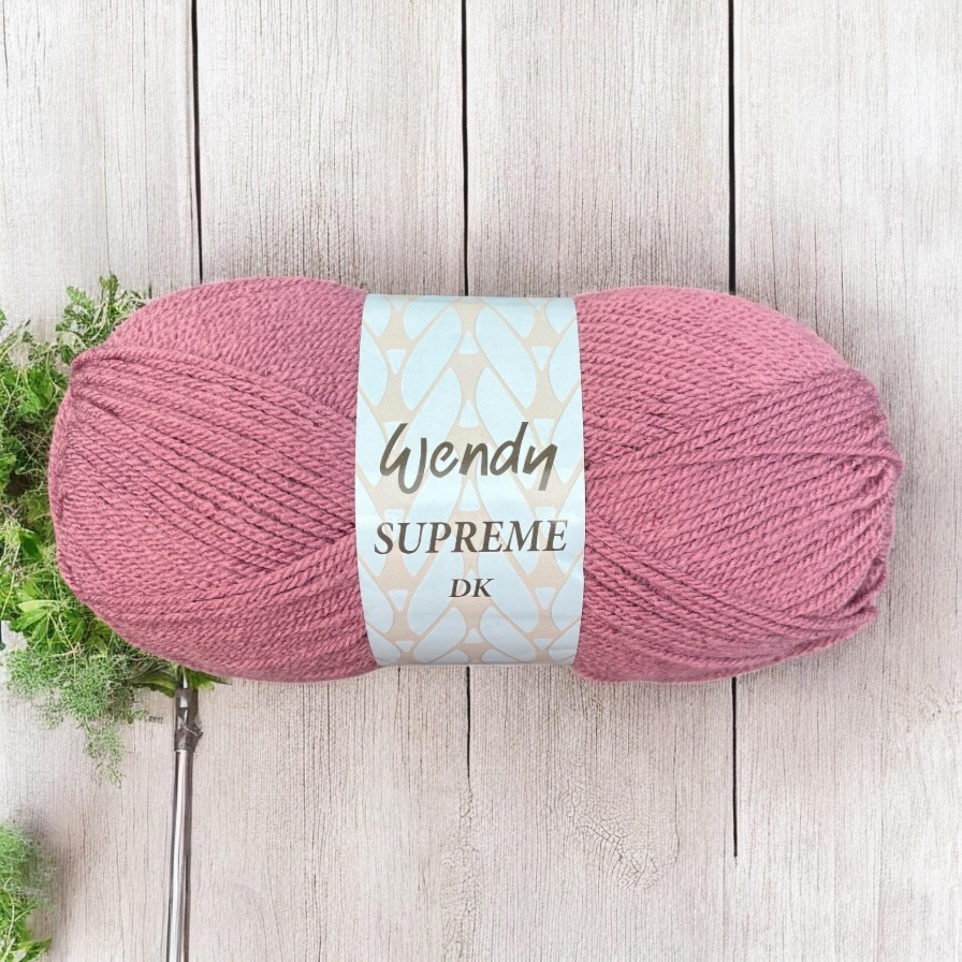Ball of Wendy Supreme DK yarn in a dusty rose colour, displayed on a light wooden background with greenery in the corner