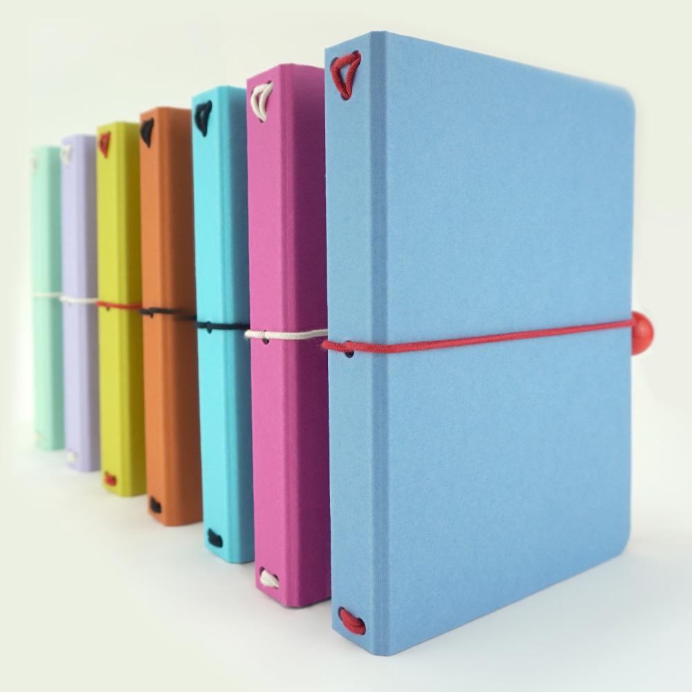 A line of bright colourful VEIDI refillable notebooks with organic elastic closure and wooden toggles