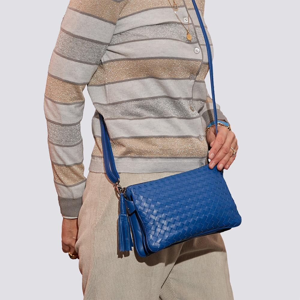 Elegant lady in metallic stripes cardigan and pans wearing an exquisite small intrecciato tote bag crafted from luxurious blue leather.