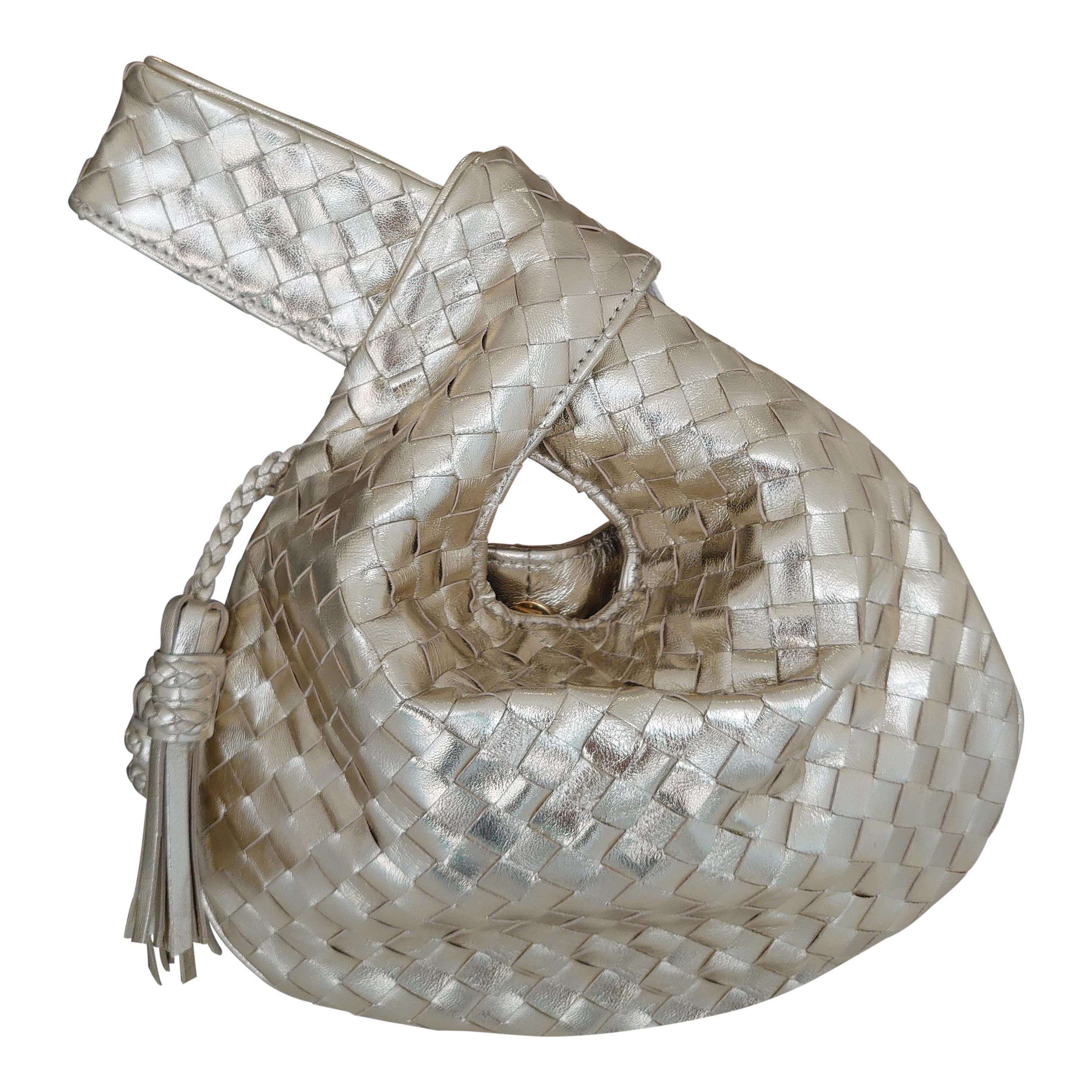 Exquisite small intrecciato evening bag in gold, with a knot at the top and two small tassels.