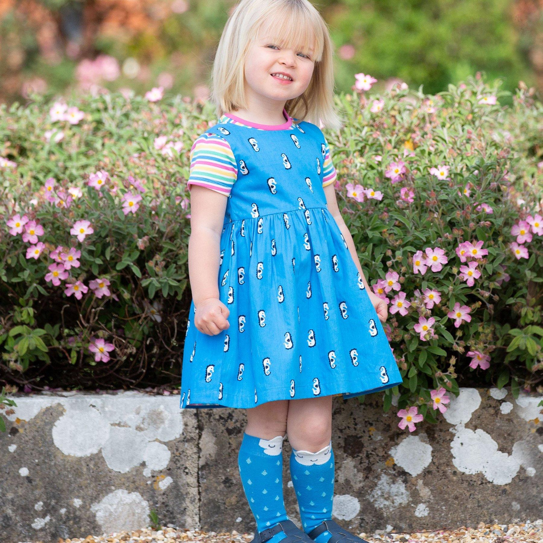 Girl wearing Kite Clothing Seahorse Reversible Stripe Dress blue