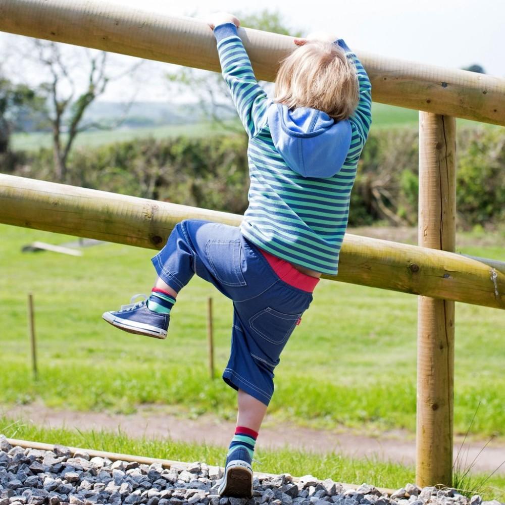 Boy wearing Kite Clothing Zig Zag Shorts climbing fence