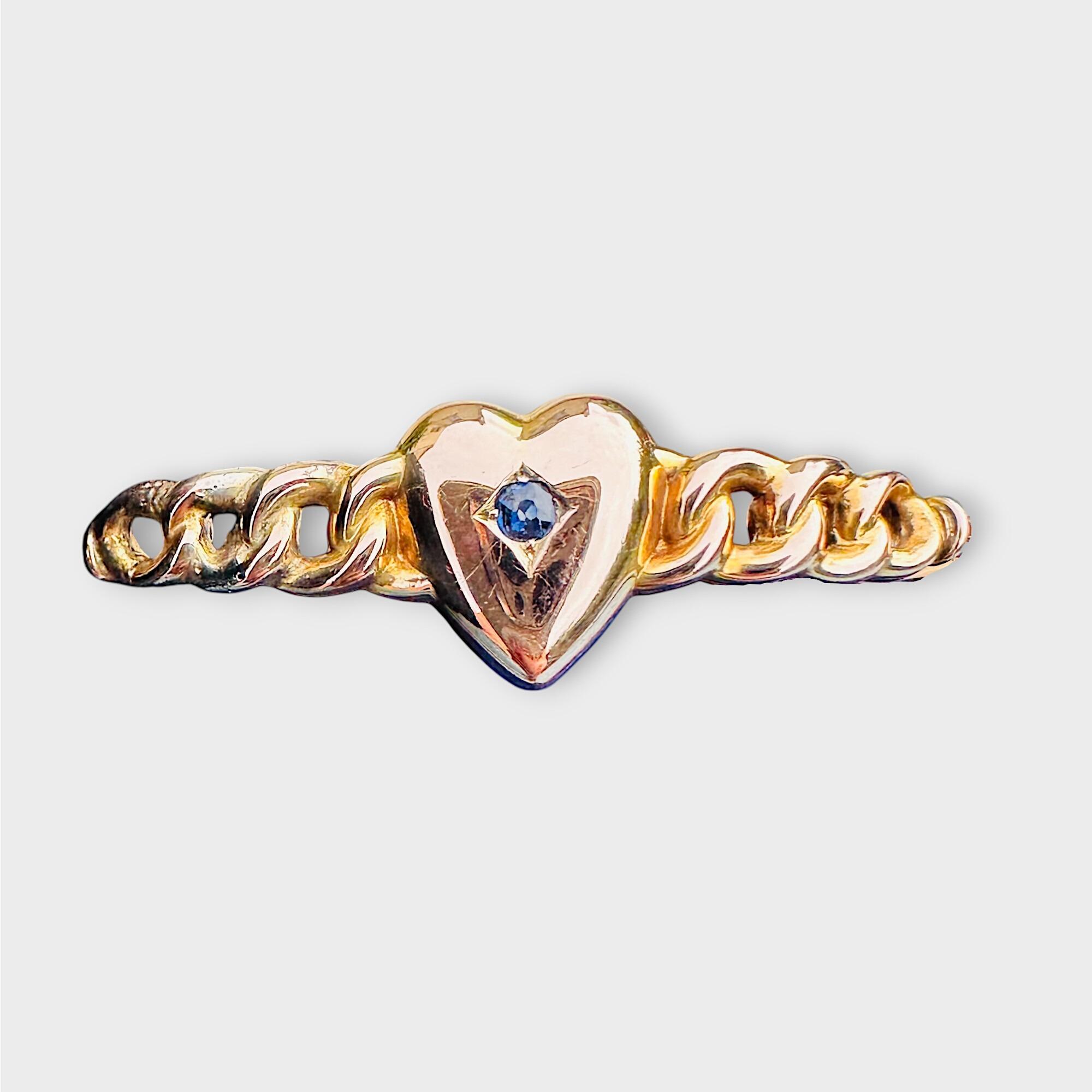 Victorian 9k gold bangle featuring a central sapphire heart, grey background.