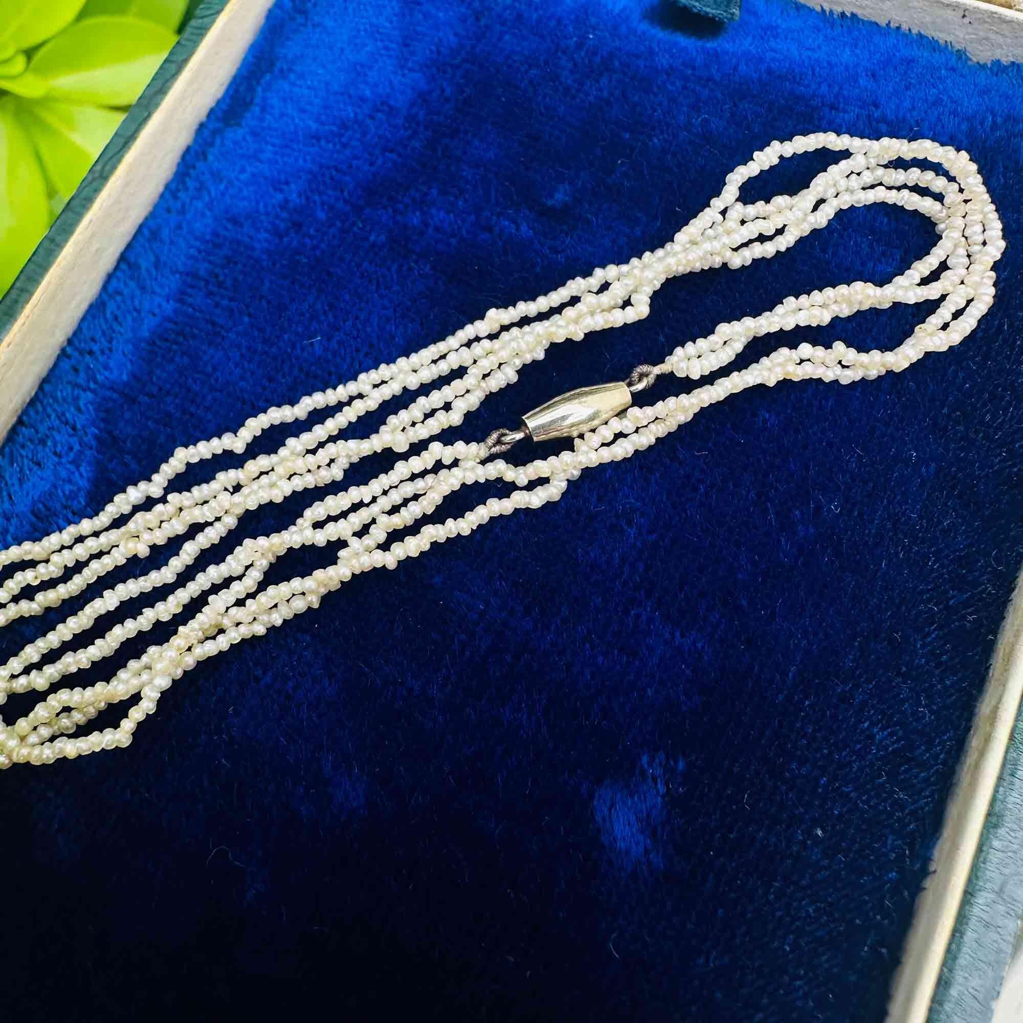 Edwardian seed pearl 2 row necklace on 18k white gold torpedo clasp on blue velvet pad.