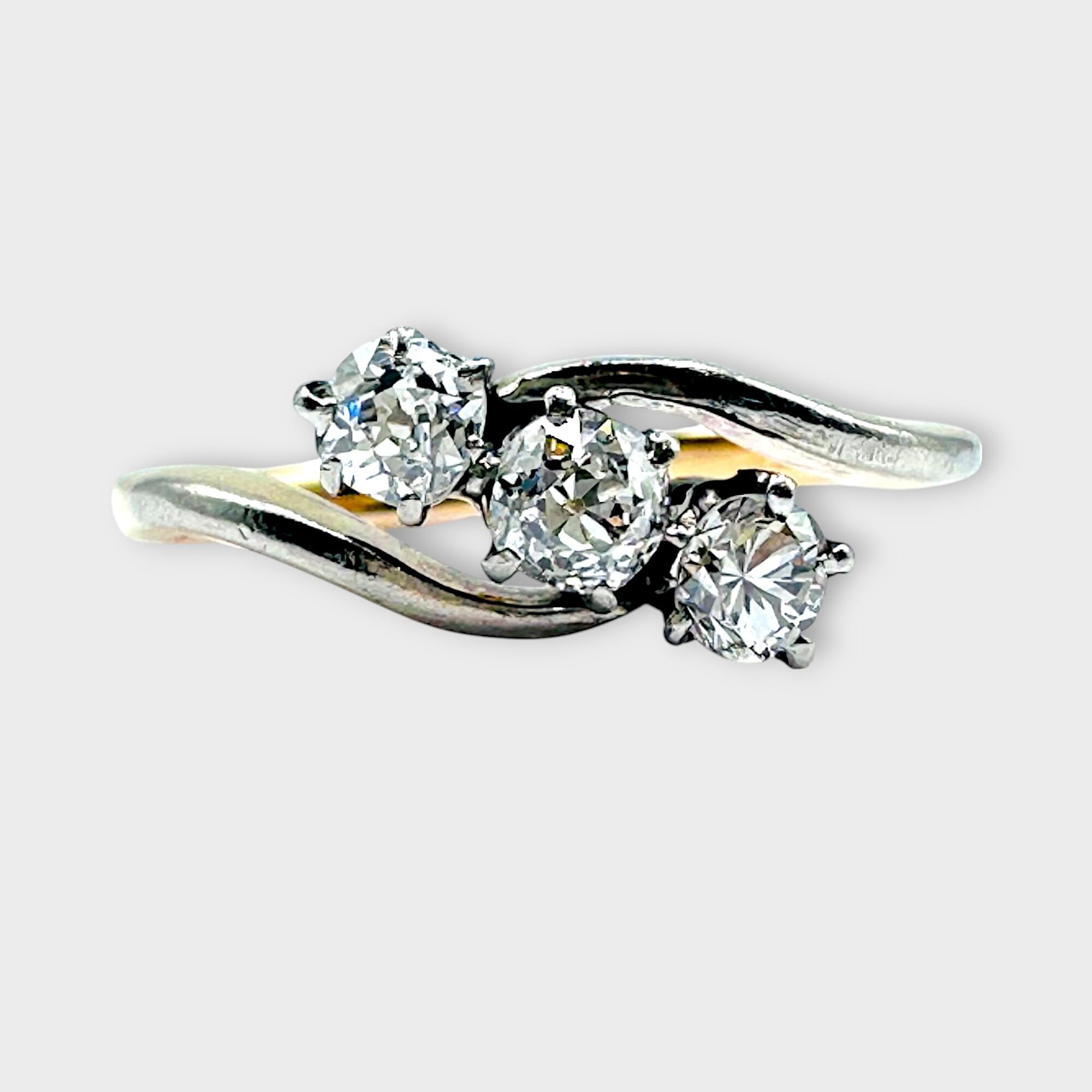Edwardian diamond trilogy ring in cross over design on grey background.