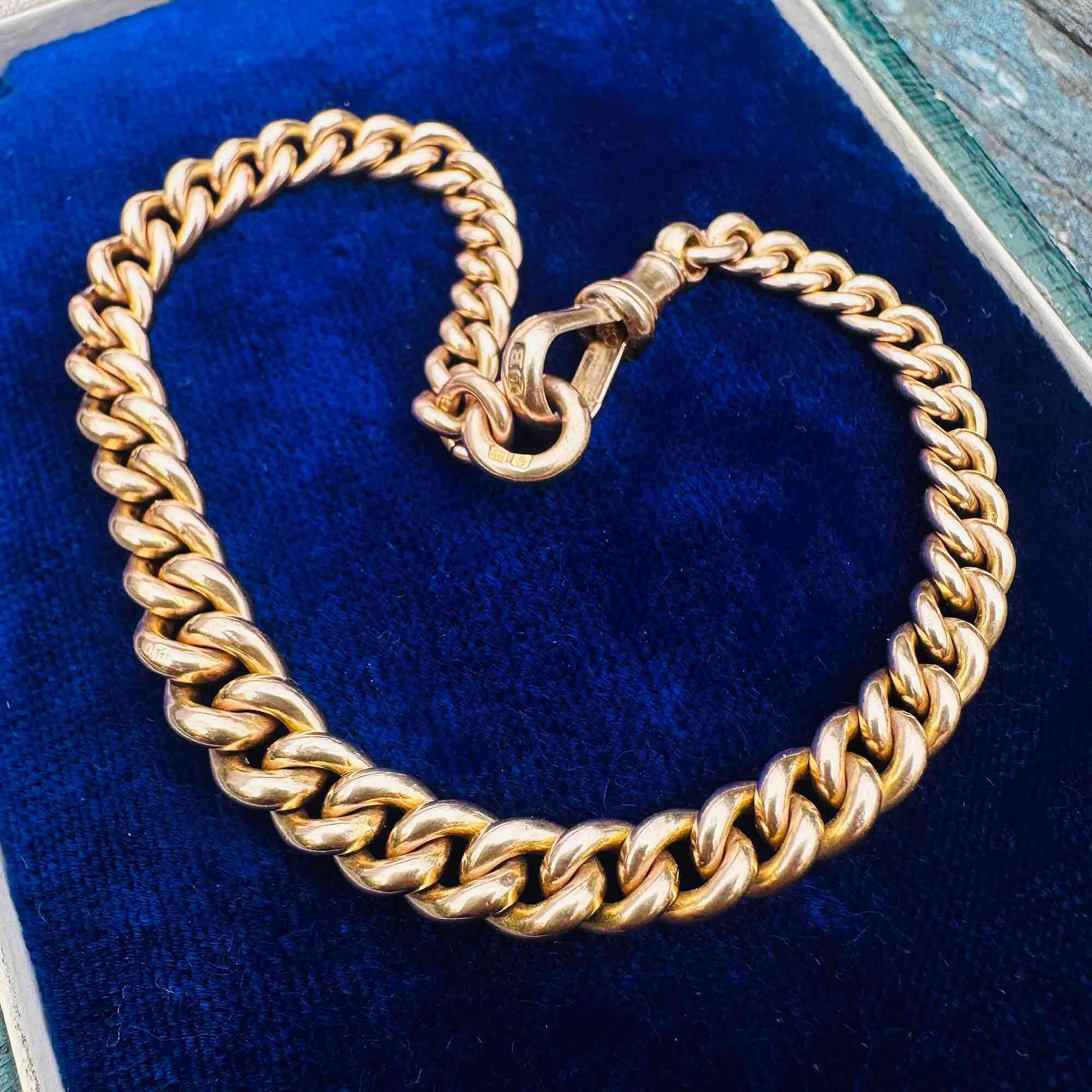 Edwardian 9ct gold curb link bracelet with traditional dog clip clasp on blue velvet pad.