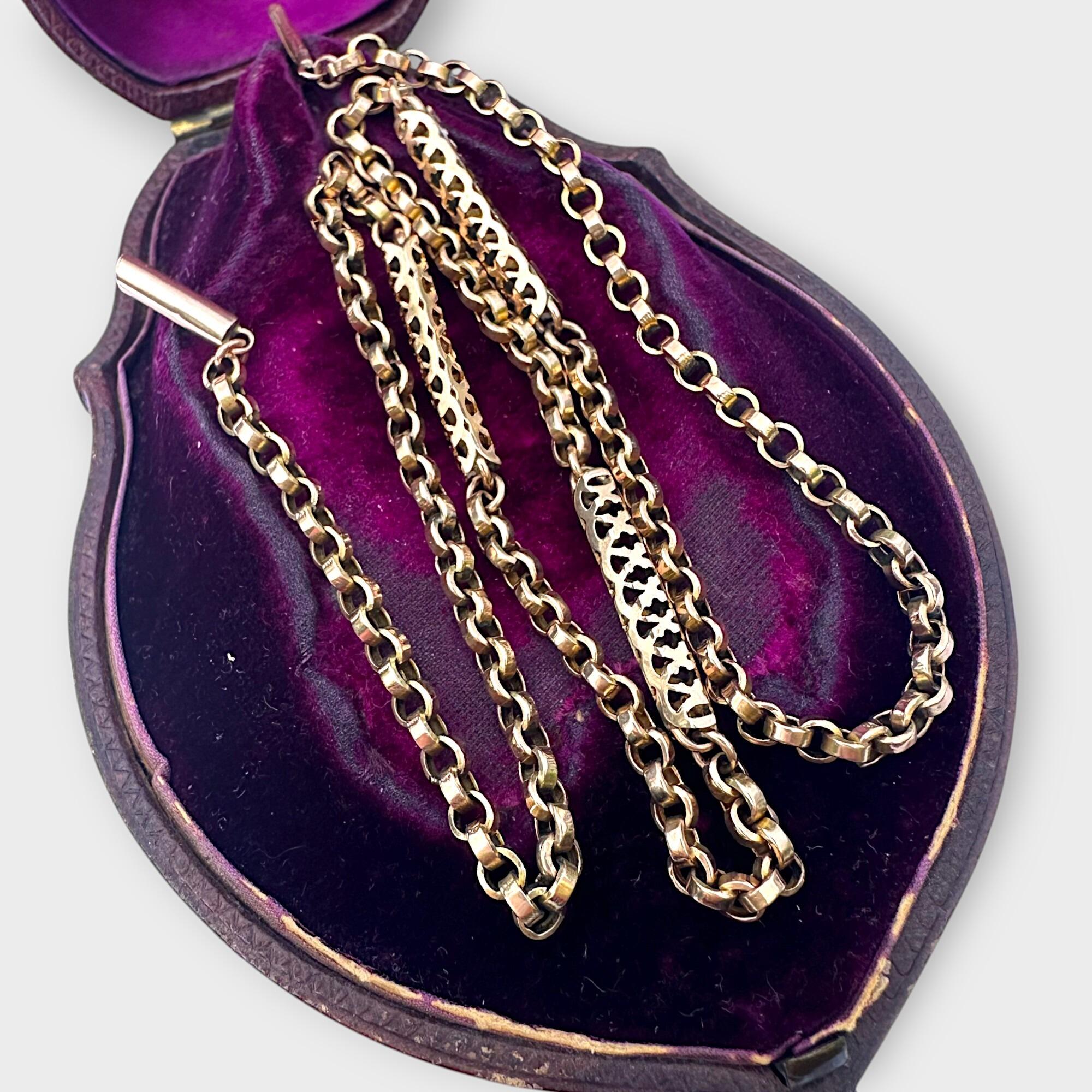 Victorian 9k gold handmade belcher chain with ornate tubular links and secure barrel clasp on antique purple velvet box with grey background.