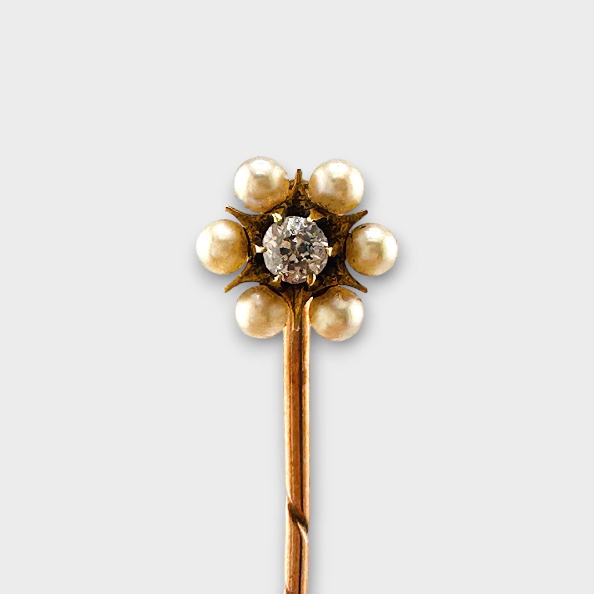 Edwardian gold, pearl and diamond daisy stick pin on grey background.