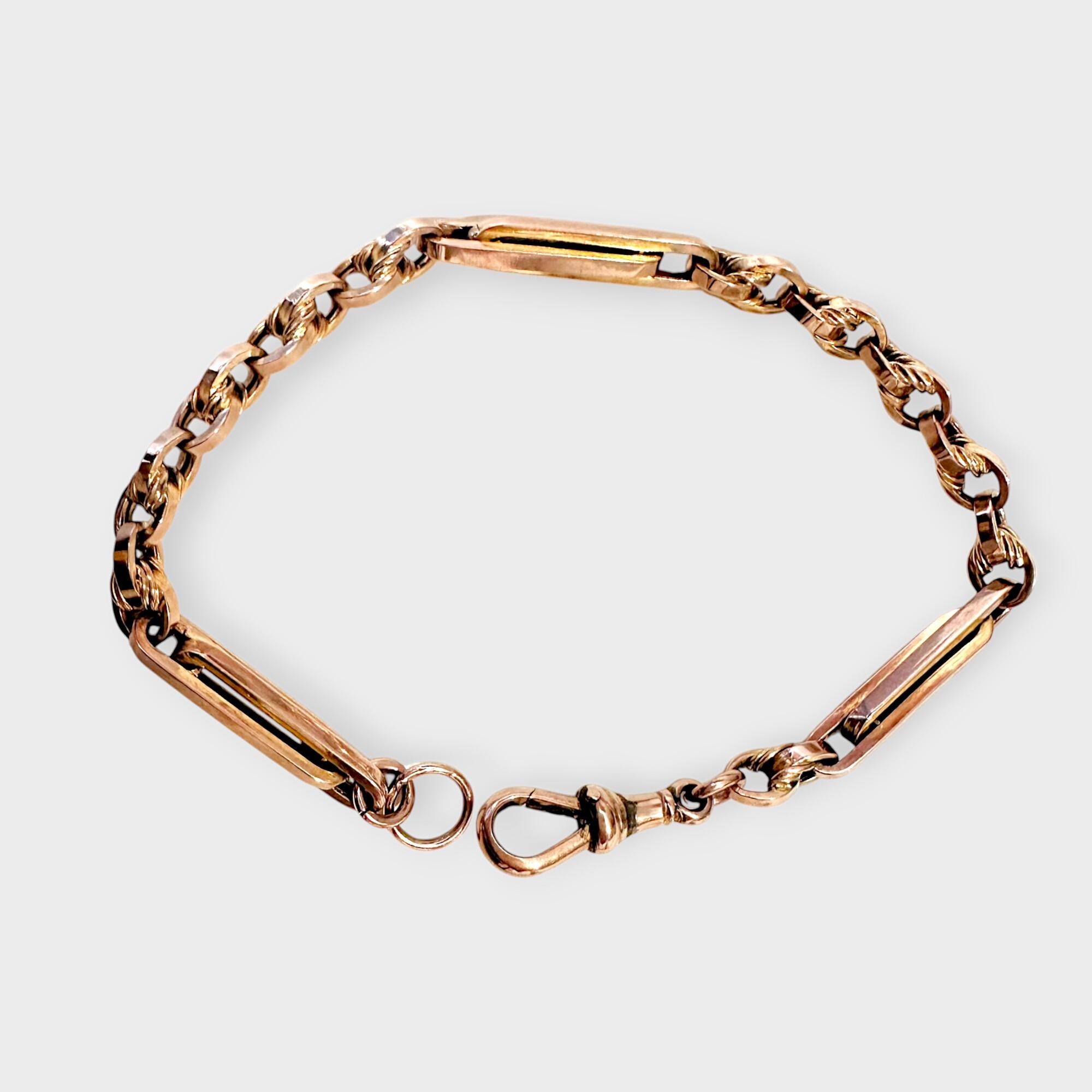 Antique 9k rose gold trombone and fancy link bracelet with dog clip clasp, 8 inches long, grey background.