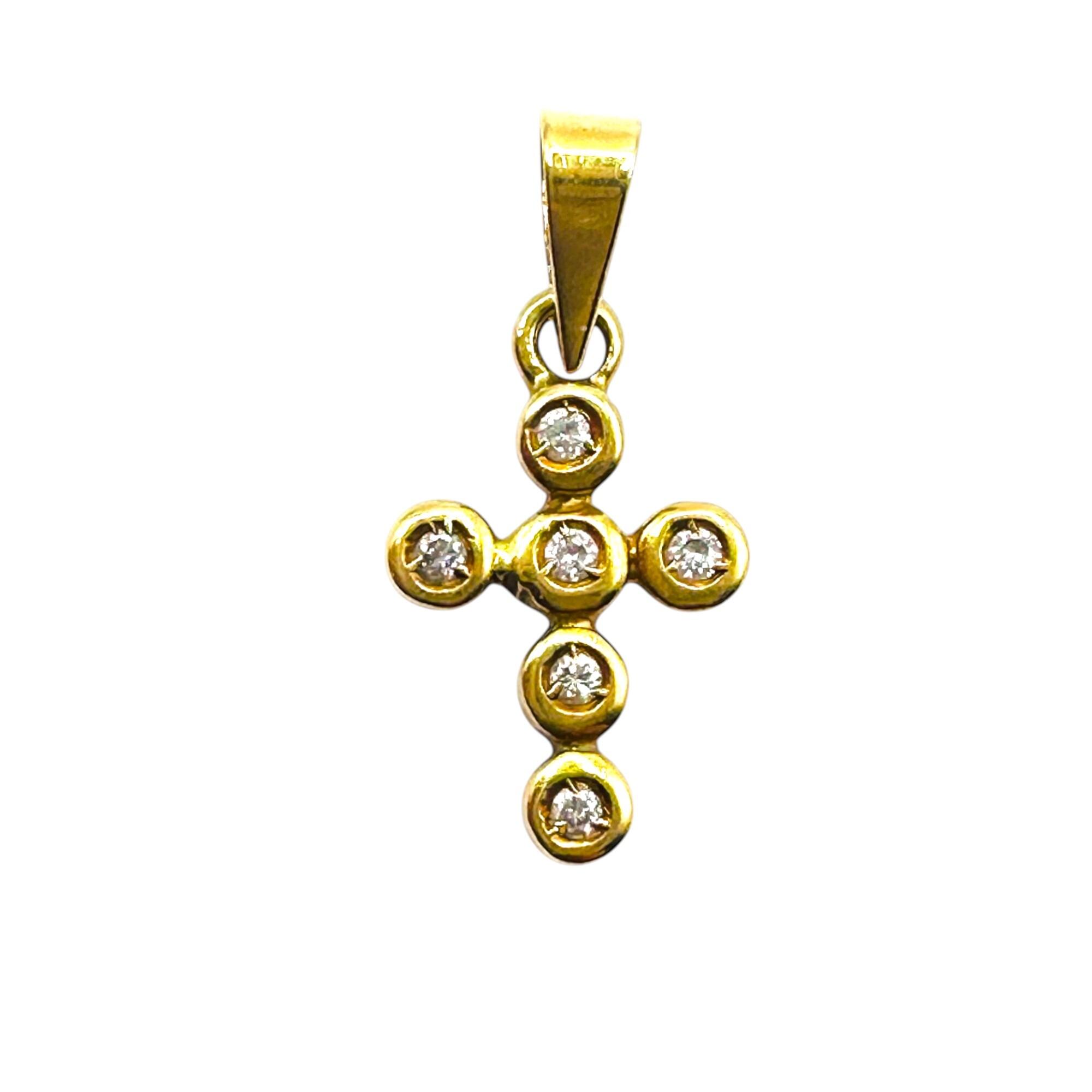 Petite18k gold diamond cross pendant on white background.