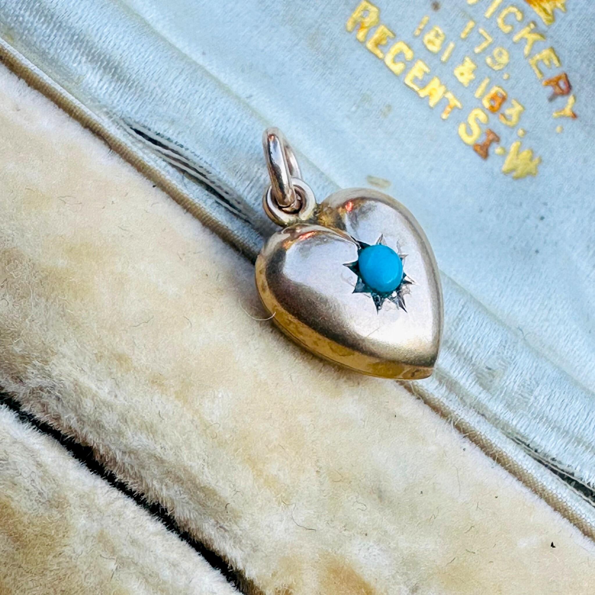 rear view of Antique Art Deco, Gold & Turquoise Puffy Heart Pendant  laying on a antique box