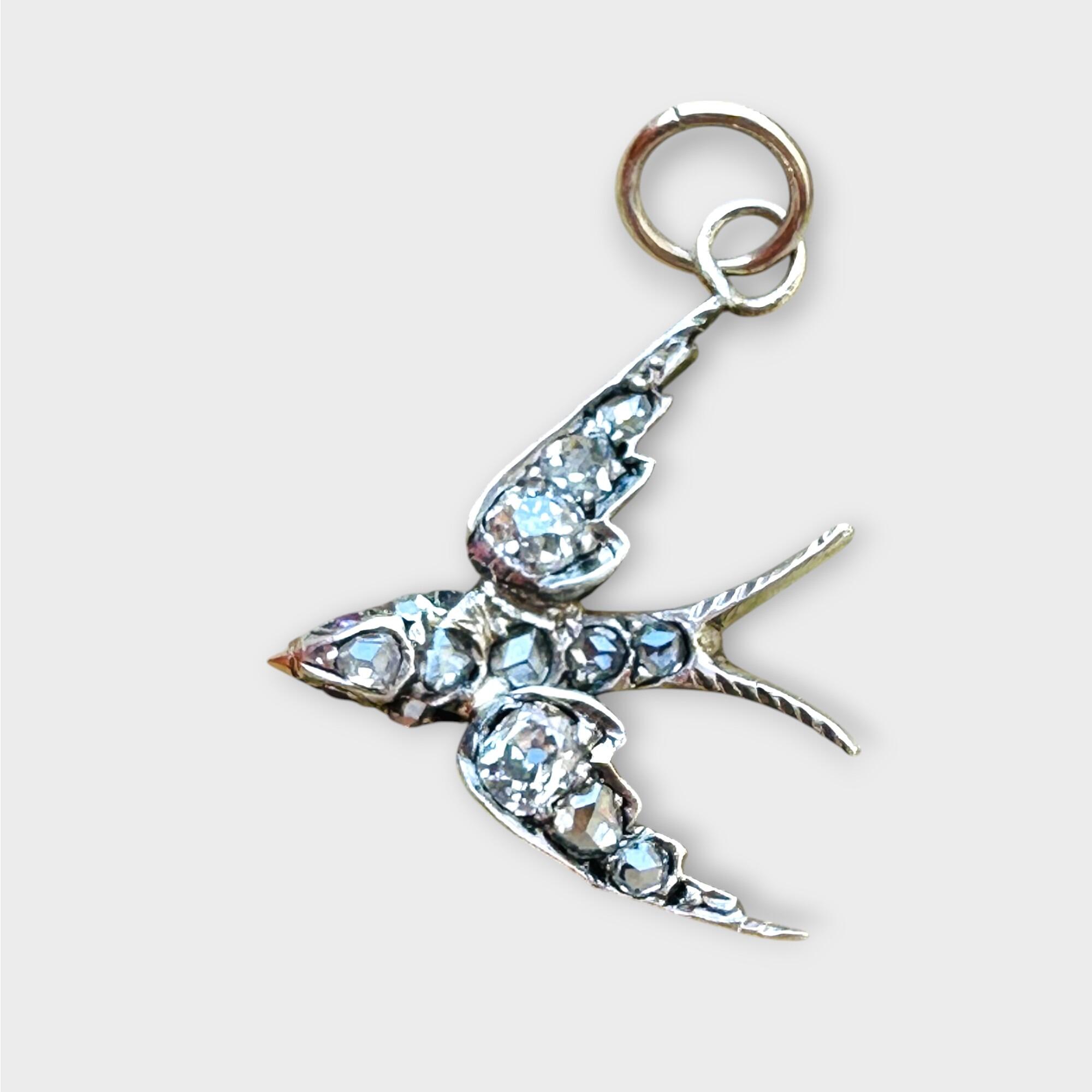 Antique diamond swallow bird pendant with ruby eyes on grey background.