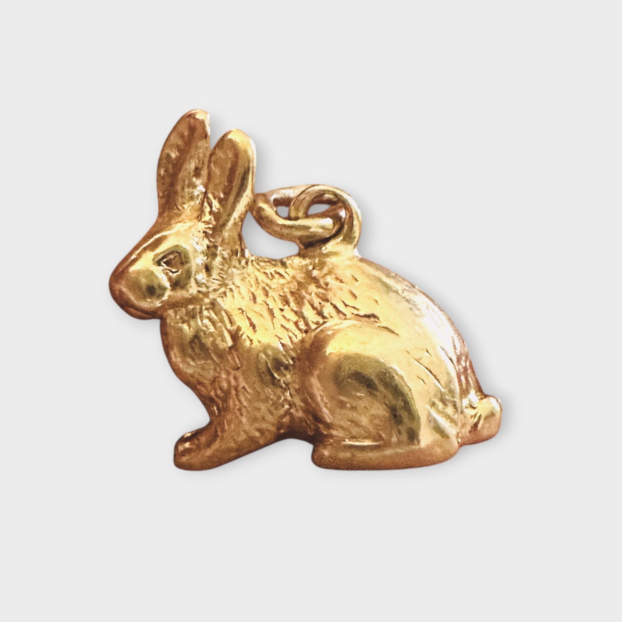 9ct gold rabbit charm on grey background.
