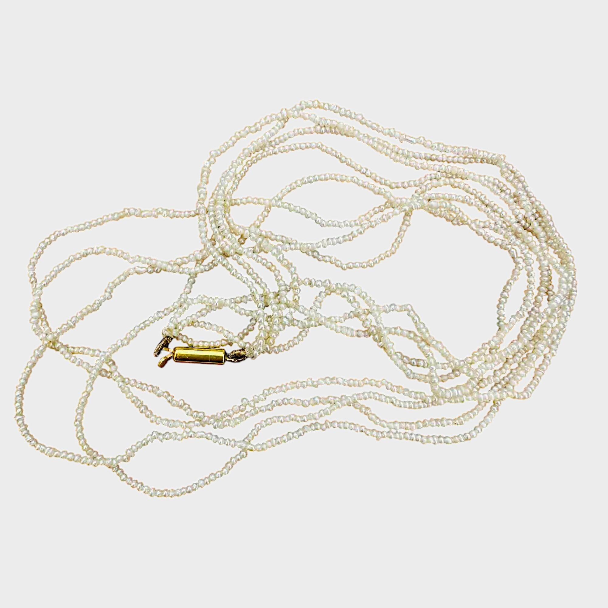 Georgian seed pearl four row necklace on 9k gold barrel clasp on grey background.