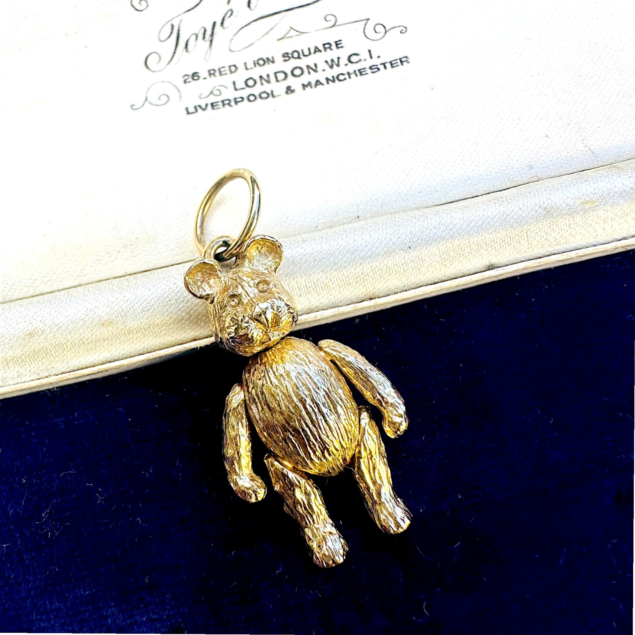 Vintage Gold Articulated Teddy Bear Charm Pendant laying on antique box