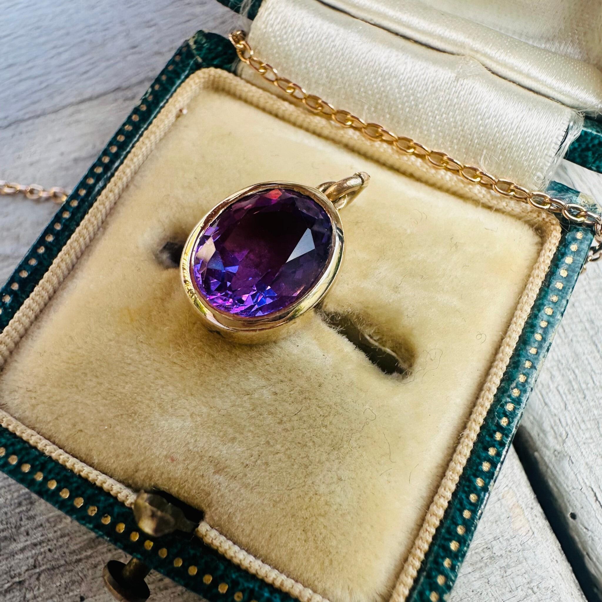 side profile of 14k Yellow Gold & Amethyst Pendant displayed on antique box