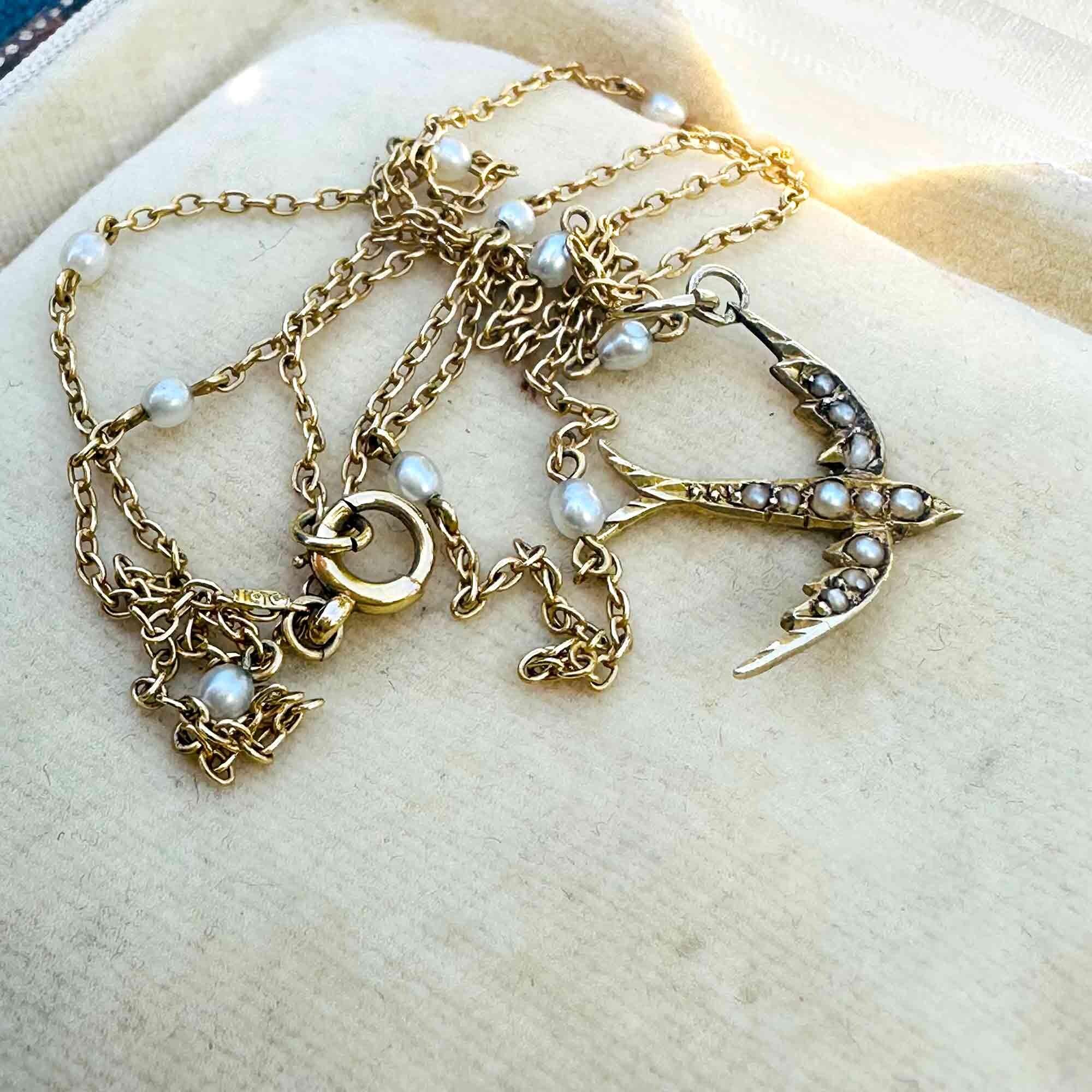 Edwardian 15k gold seed pearl swallow pendant / charm displayed with antique pearl chain on antique box.