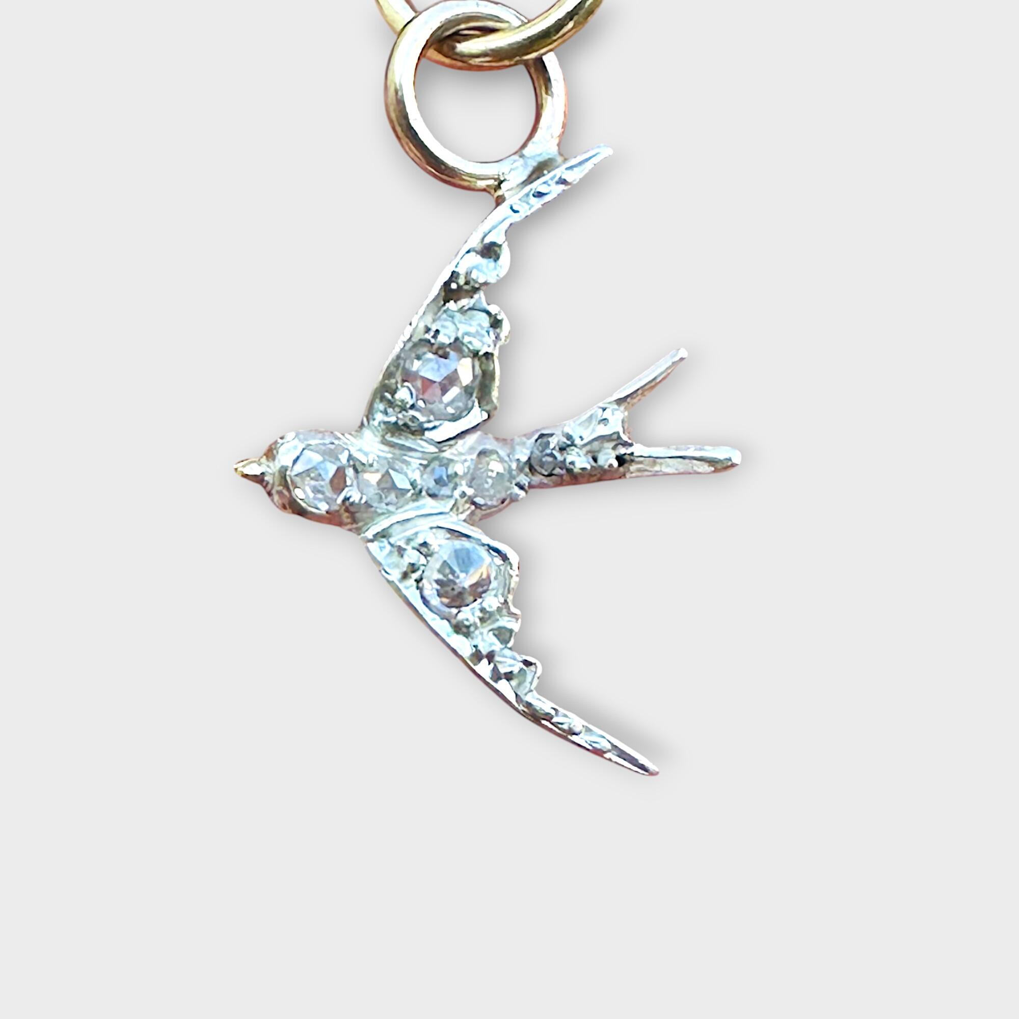 Victorian diamond swallow pendant on grey background.