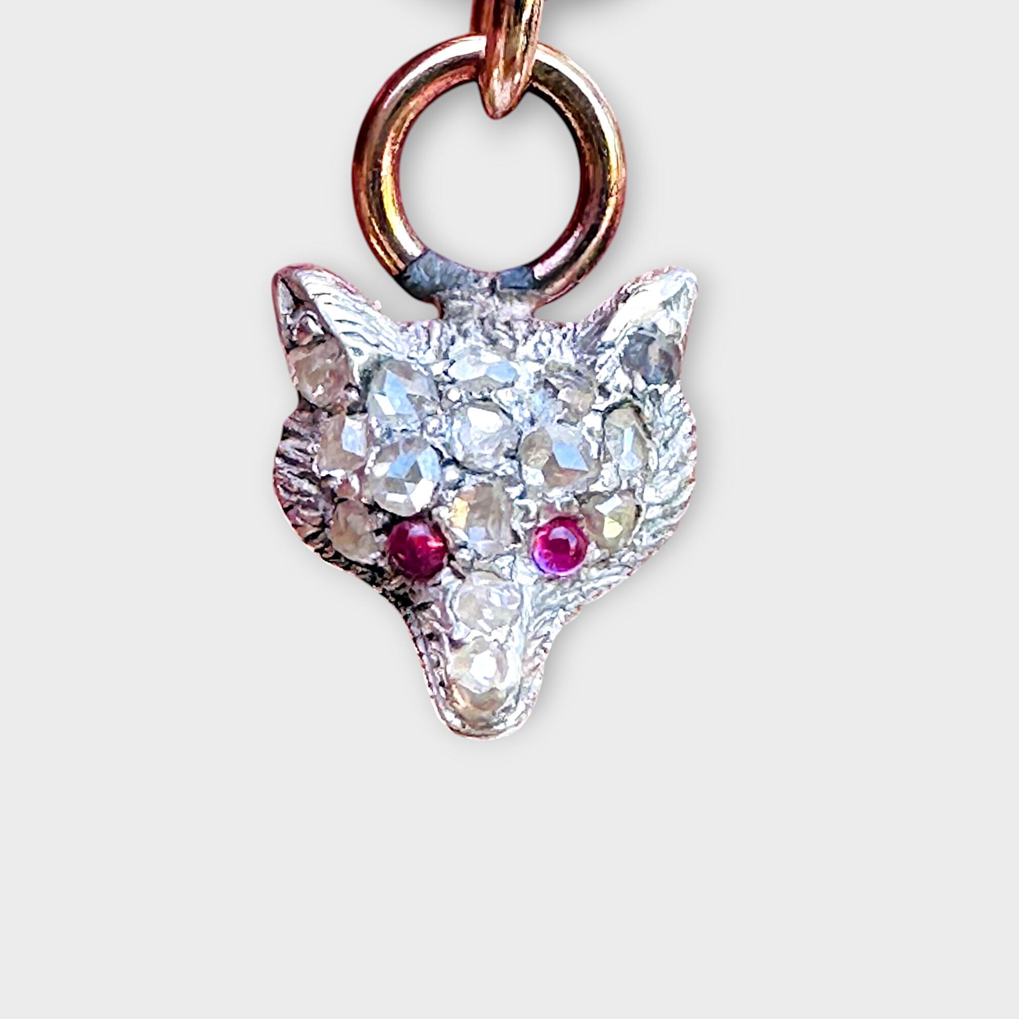 Victorian diamond and ruby fox head charm / pendant on grey background.