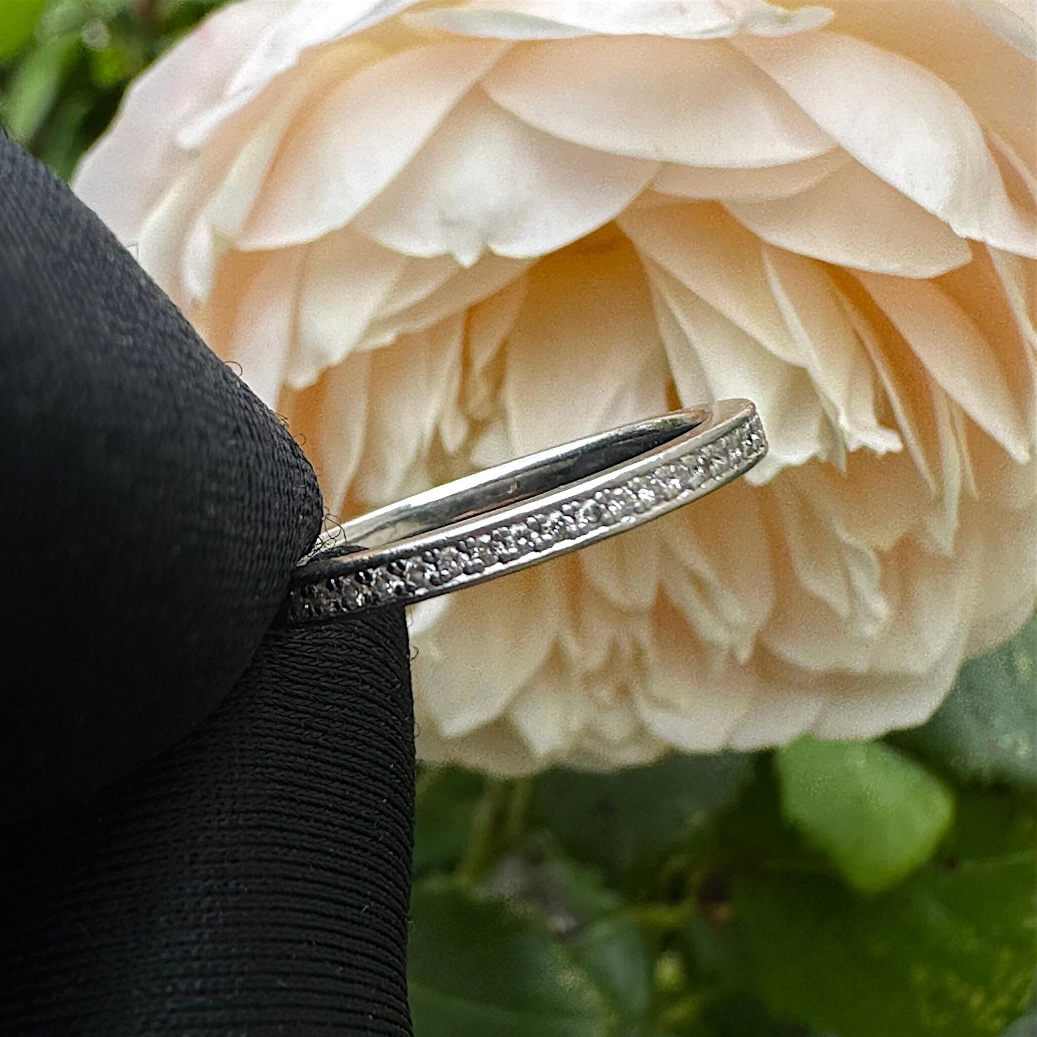 Vintage Platinum Diamond Eternity Ring, Wedding Band held in gloved hand with flower background