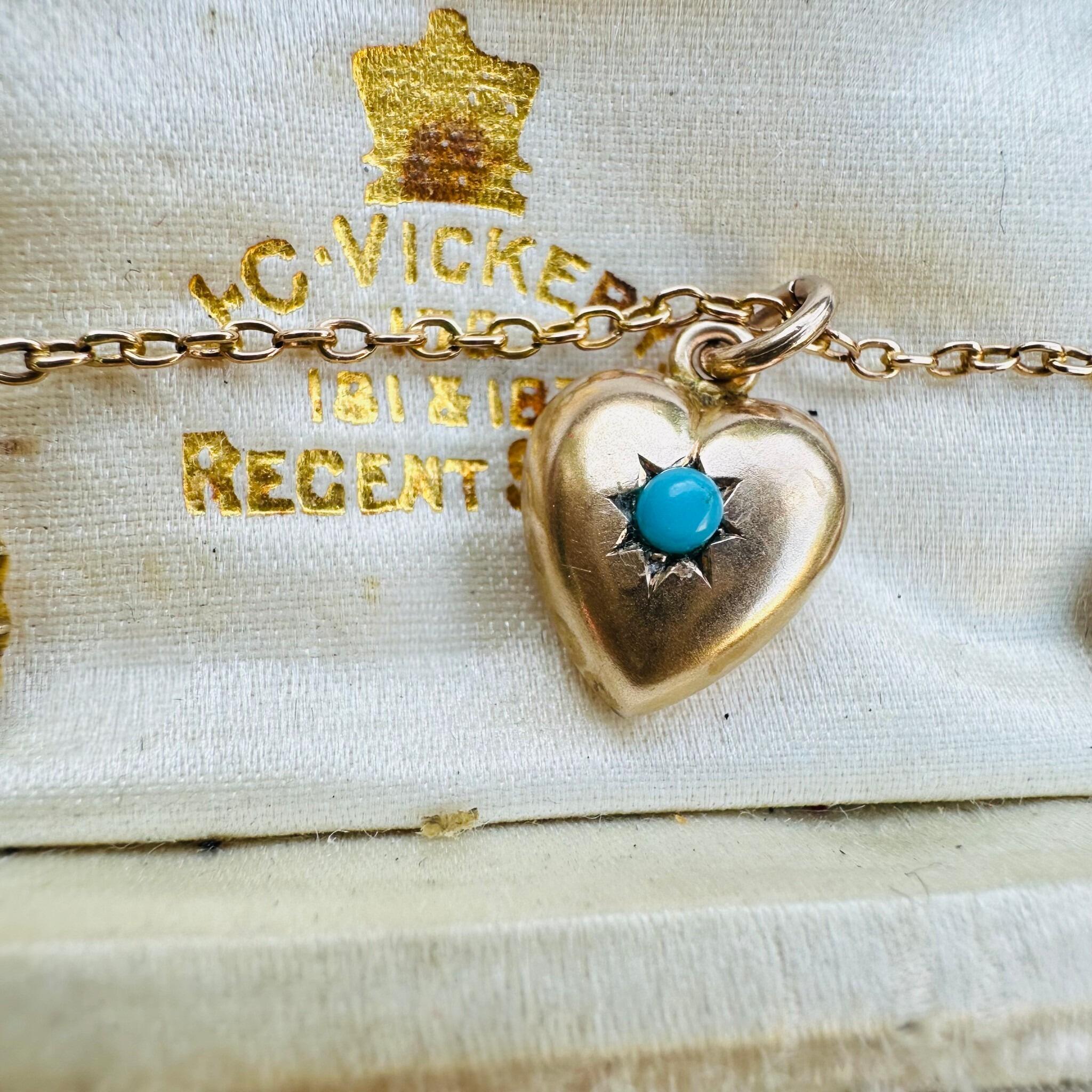 front view of Antique Art Deco, Gold & Turquoise Puffy Heart Pendant laying on a antique box