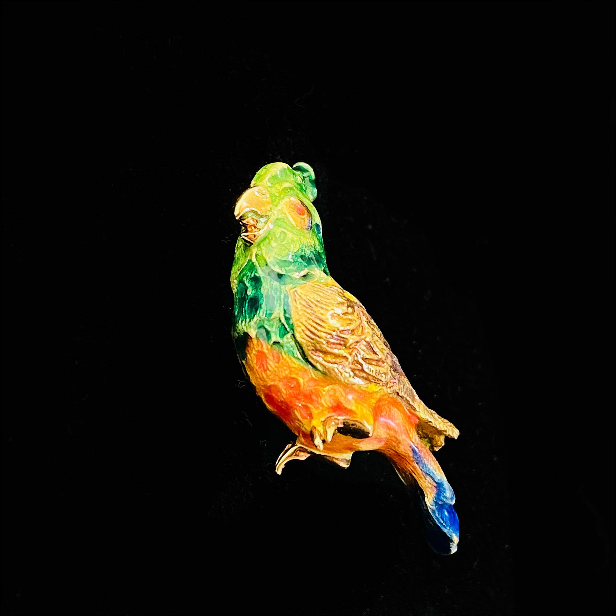 Charming parrot brooch in 18ct yellow gold with colorful enameling and feather detailing, measuring 28 x 9mm. Vintage piece in excellent condition.