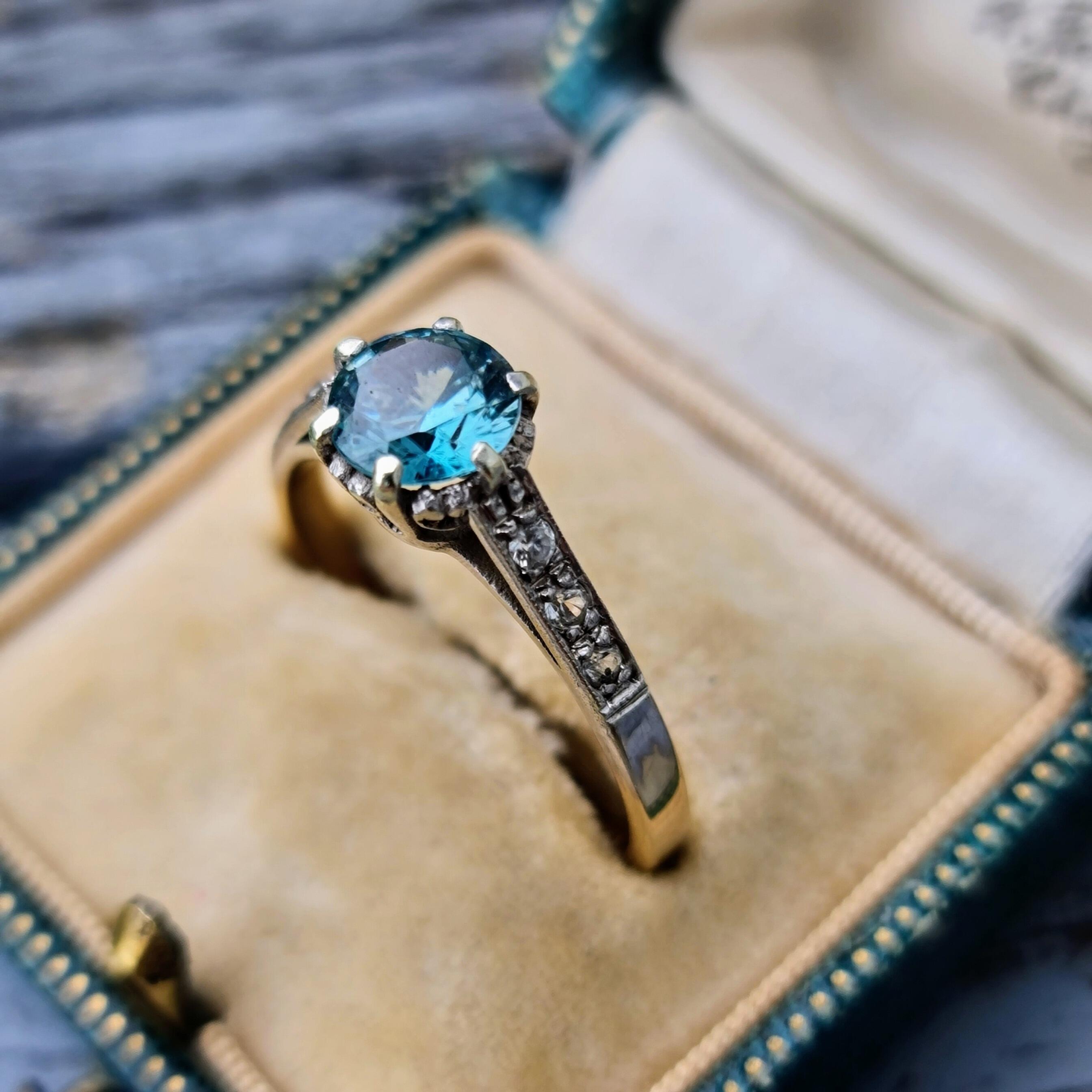 Stunning Art Deco ring with central blue zircon in white gold crown setting, heart details, and decorative shoulders, 9ct gold.