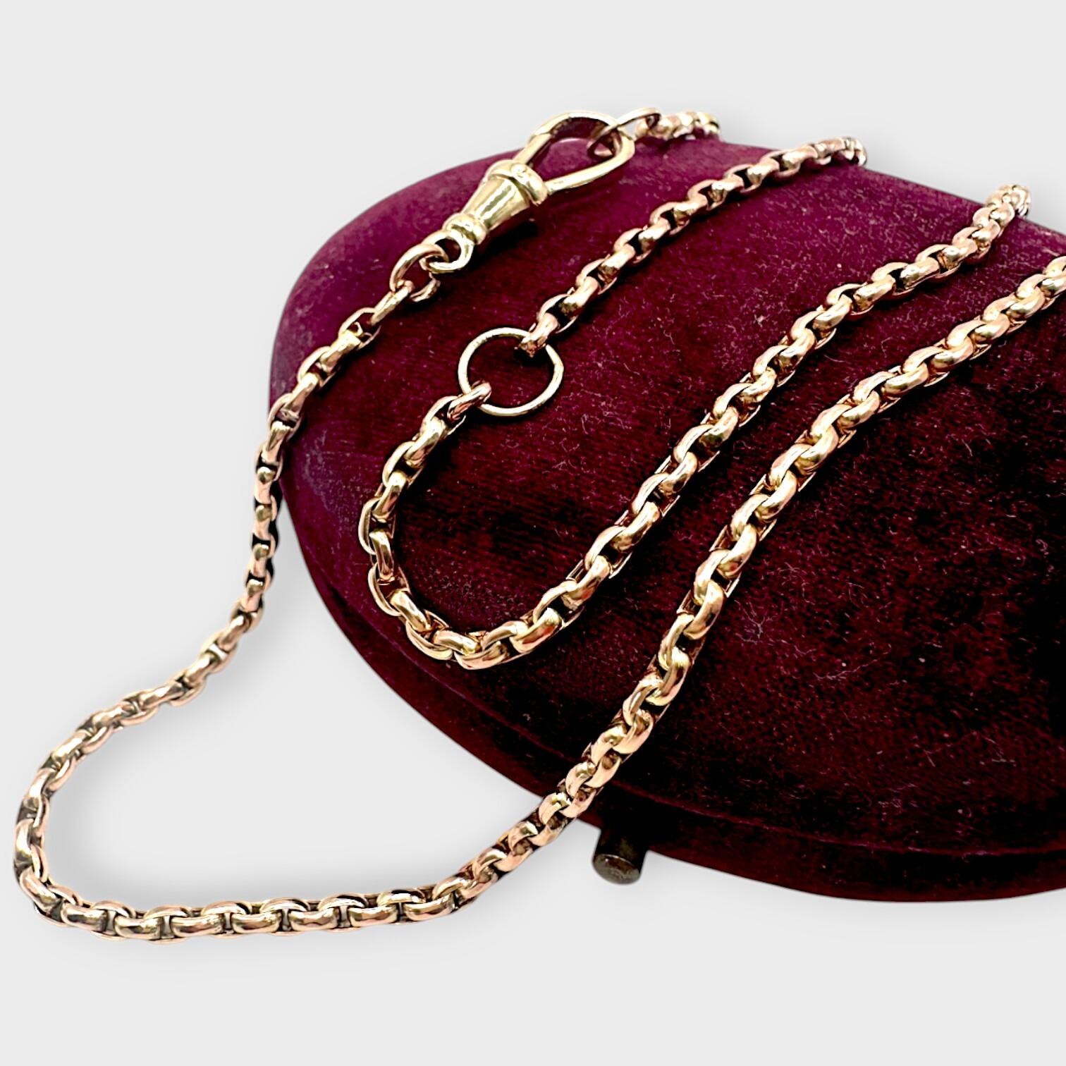 Victorian 9ct gold faceted belcher link chain with dog clip clasp, draped over burgundy velvet case with grey background.