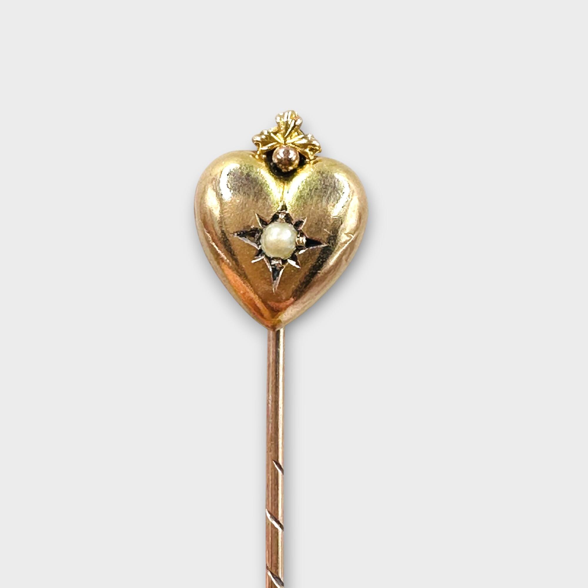 Victorian 9ct gold puffy heart stick pin with central pearl on grey background.