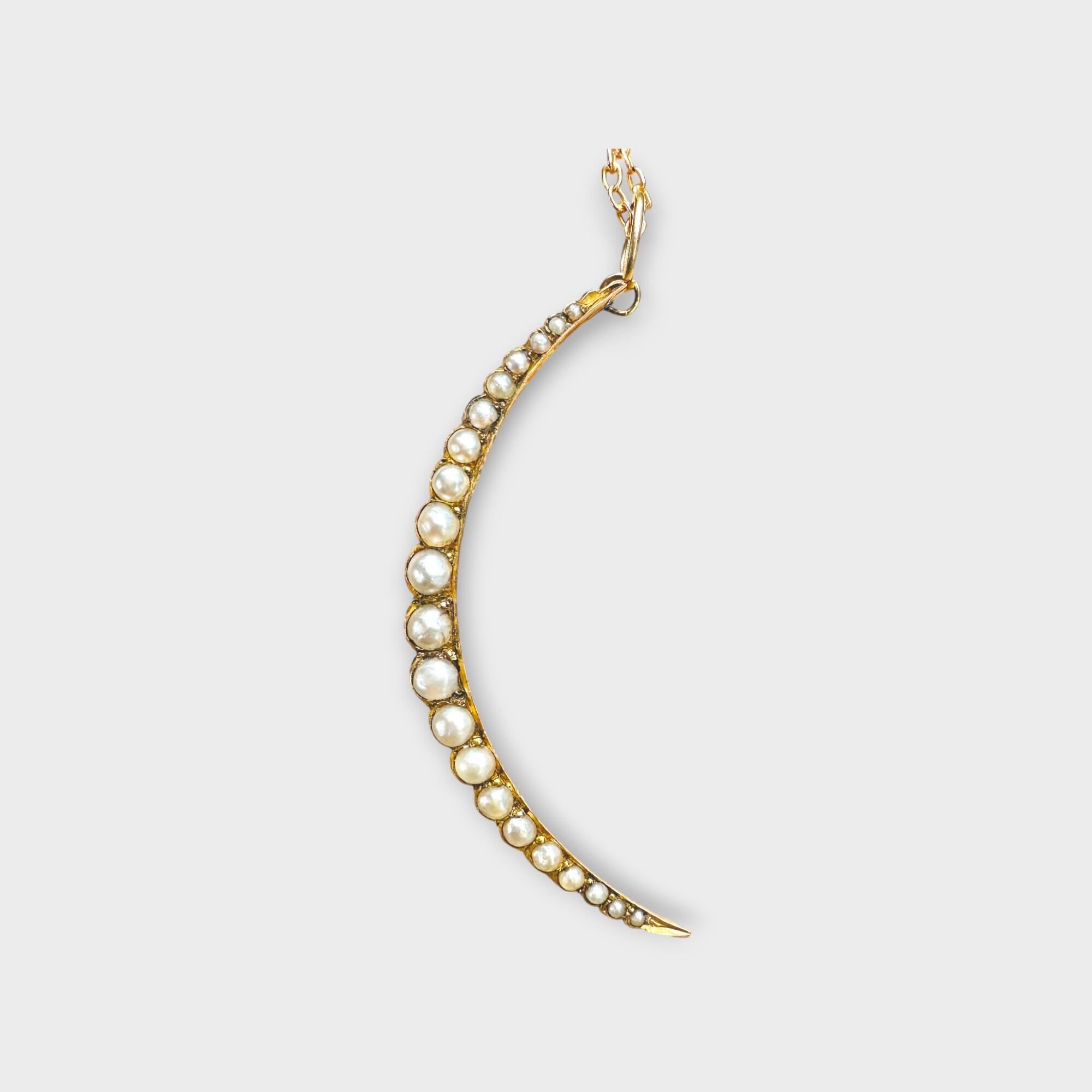 Victorian 9k gold crescent pearl pendant on grey background.