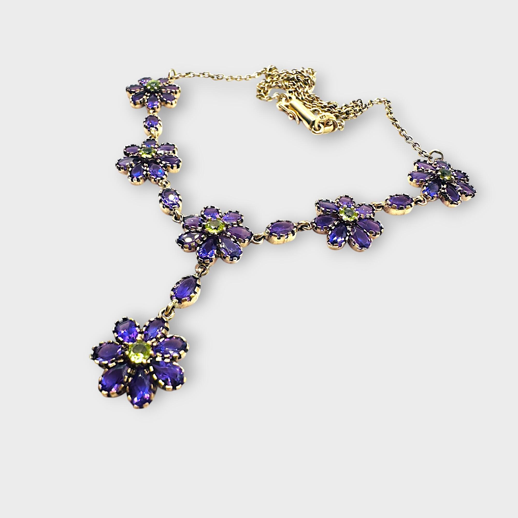 Art Nouveau 9k gold Amethyst and Peridot suffragette lavaliere necklace on grey background.