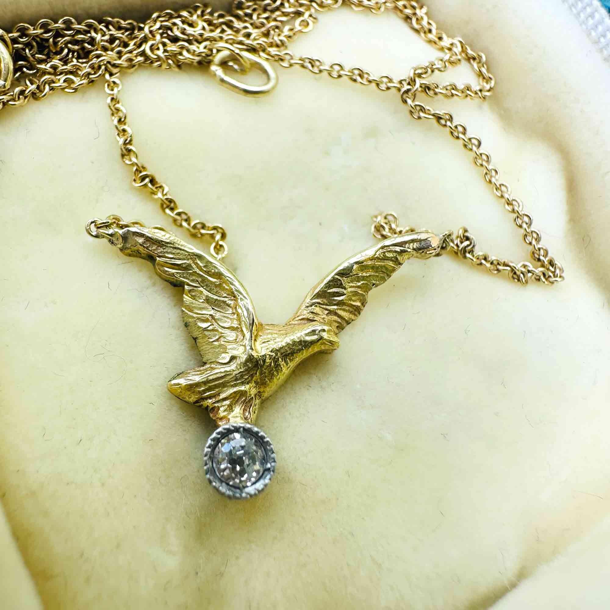 Front view of 18K gold eagle pendant necklace with a sparkling diamond in the eagle’s beak, in a antique box.