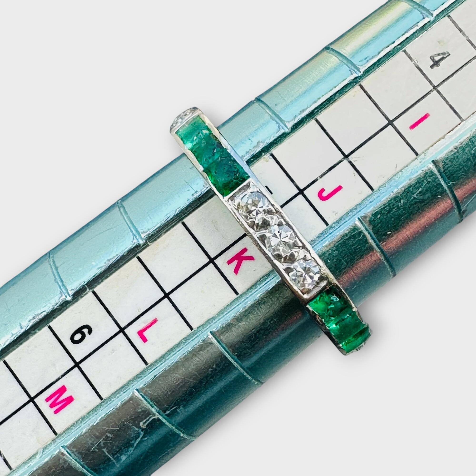 Emerald and diamond full eternity ring designed to be worn alone or stacked with other bands, displayed on ring sizer.