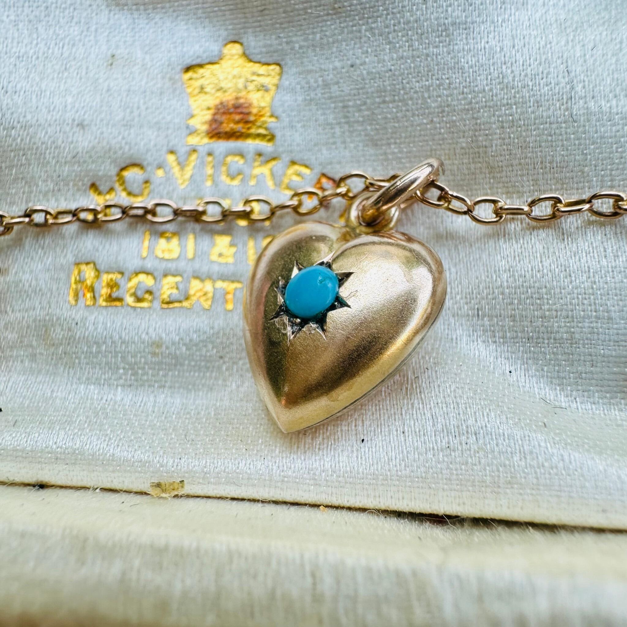 side view of Antique Art Deco, Gold & Turquoise Puffy Heart Pendant  laying on a antique box