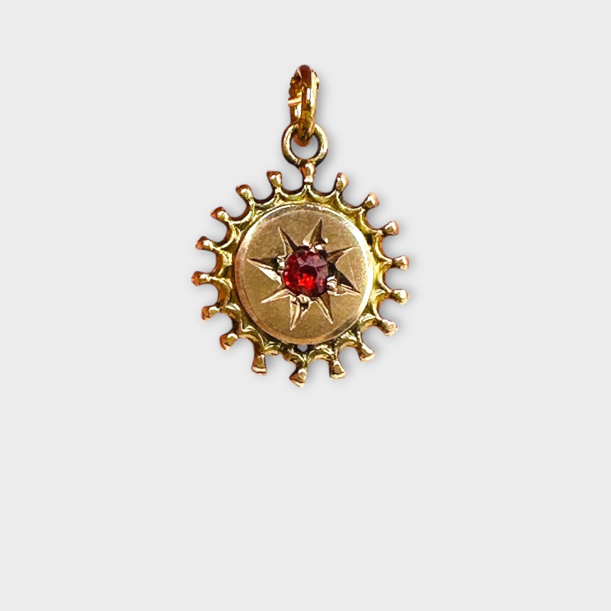 Victorian 9ct Gold, Sunburst Charm / Pendant with red paste on grey background.