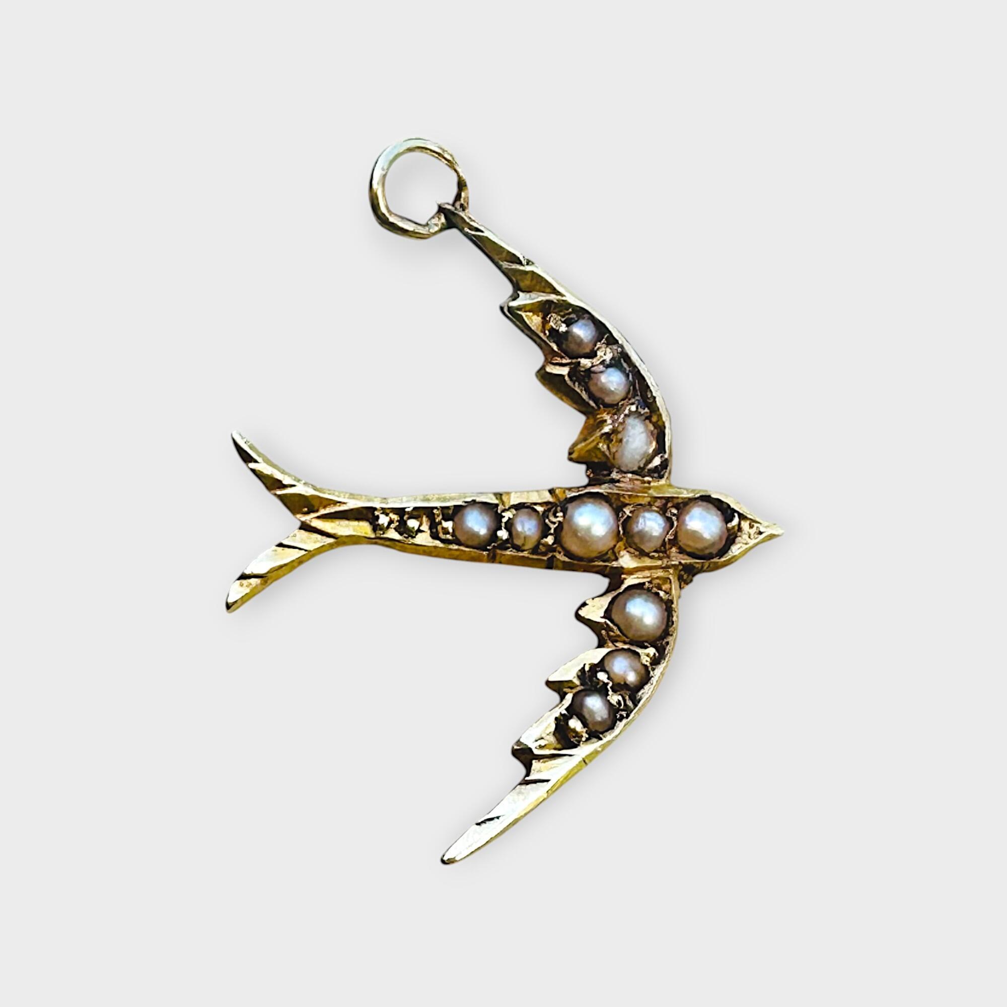 Edwardian 15k gold seed pearl swallow pendant / charm on grey background.