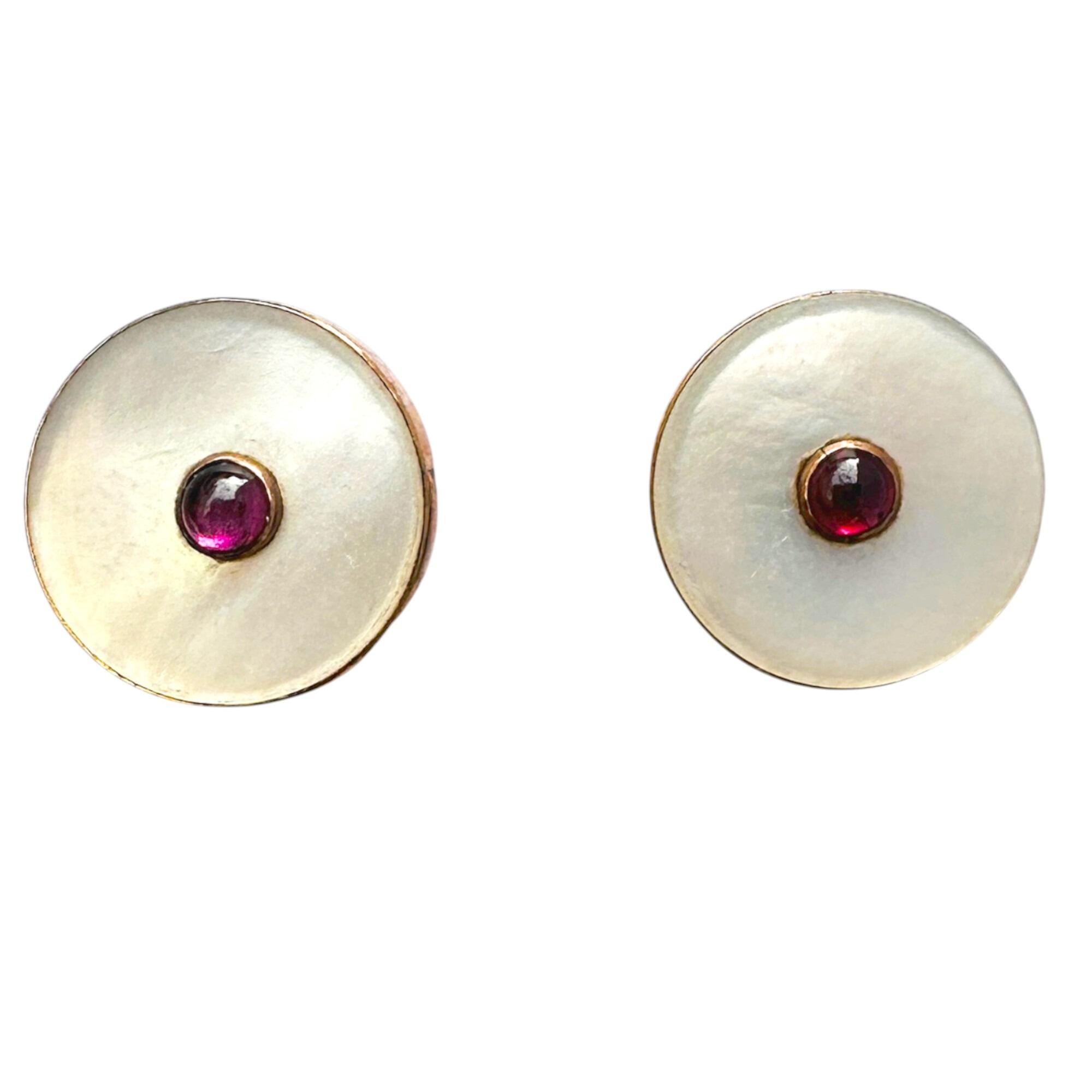 close up of Art Deco 9ct gold earrings with ruby and mother of pearl on White background.