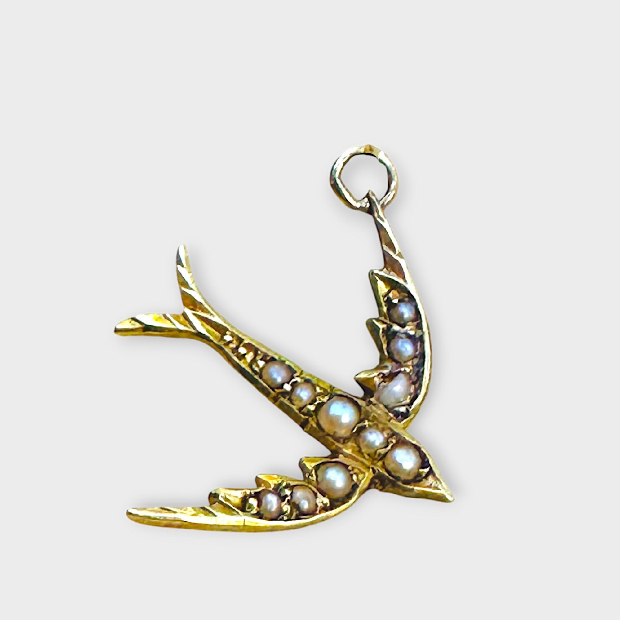 Edwardian 15k gold seed pearl swallow pendant / charm on grey background.