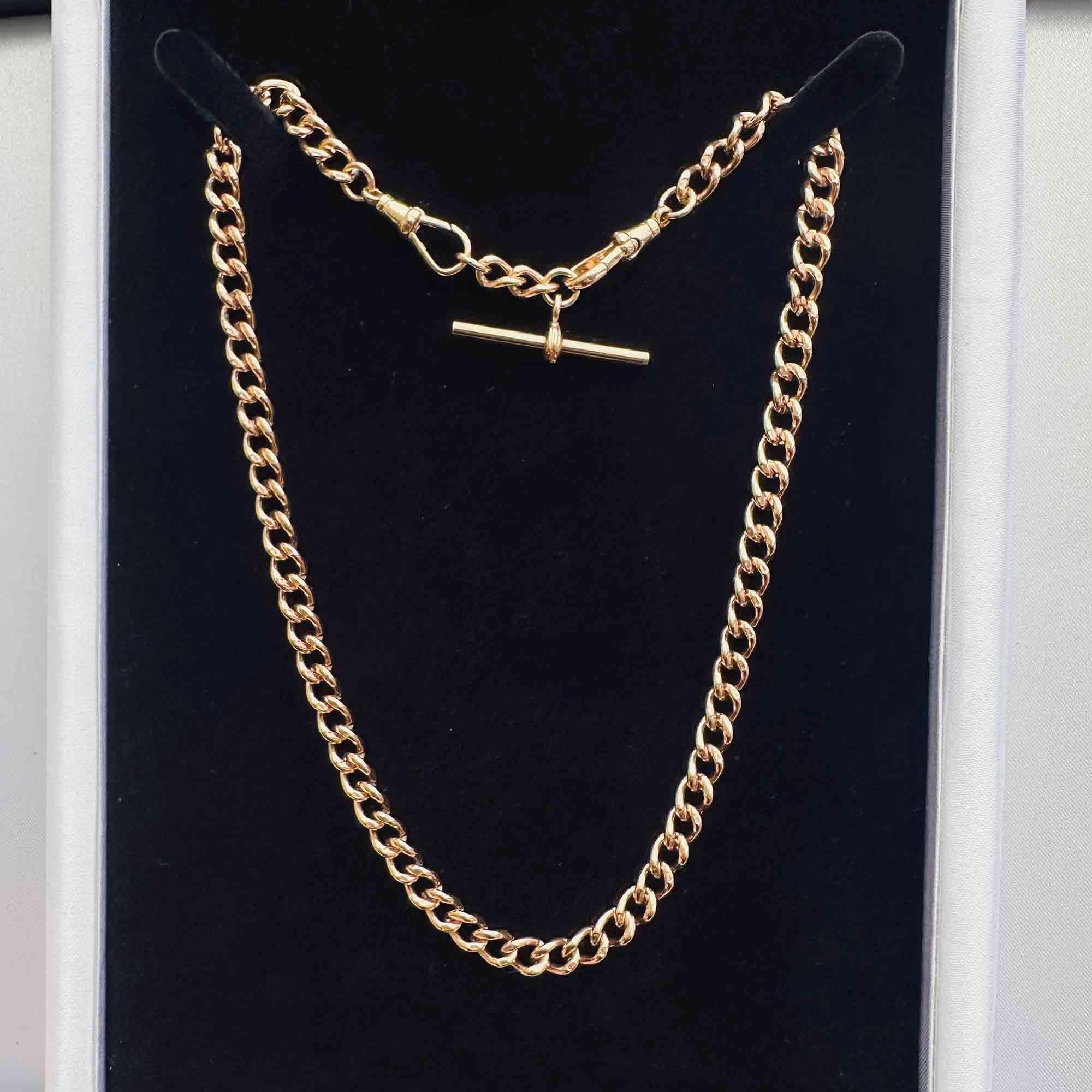 Edwardian 9ct rose gold chain with T-bar and dog clip fittings displayed on black velvet.