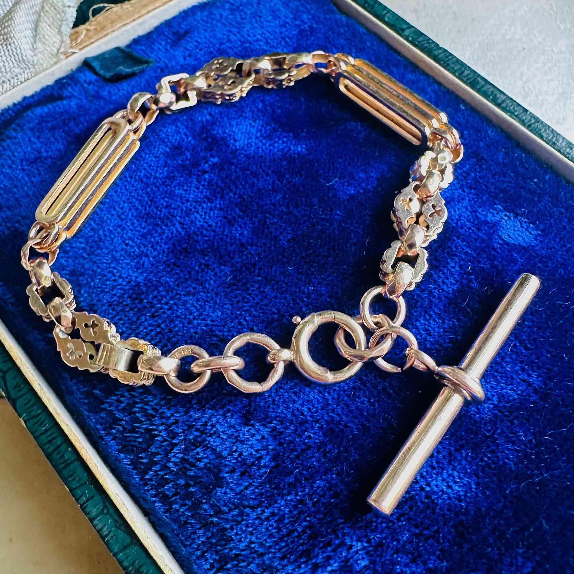 Victorian 9ct rose gold fancy link bracelet with star bar and faceted belcher chain, displayed coiled on a blue velvet box.