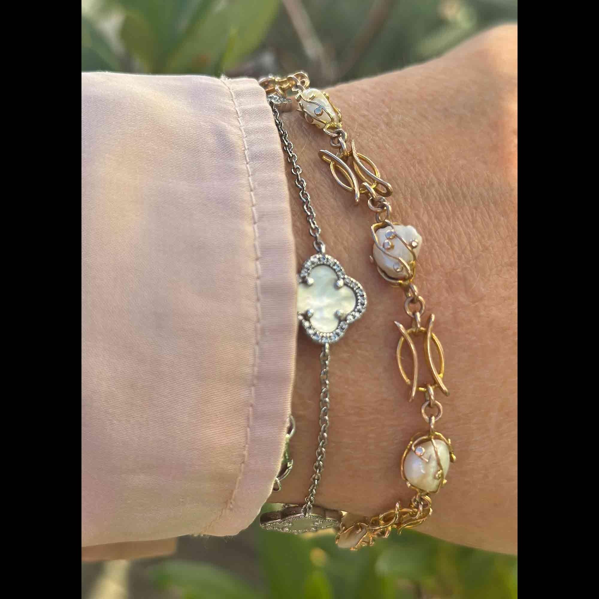 Art nouveau 9k rose gold cage pearl bracelet worn on models wrist in garden